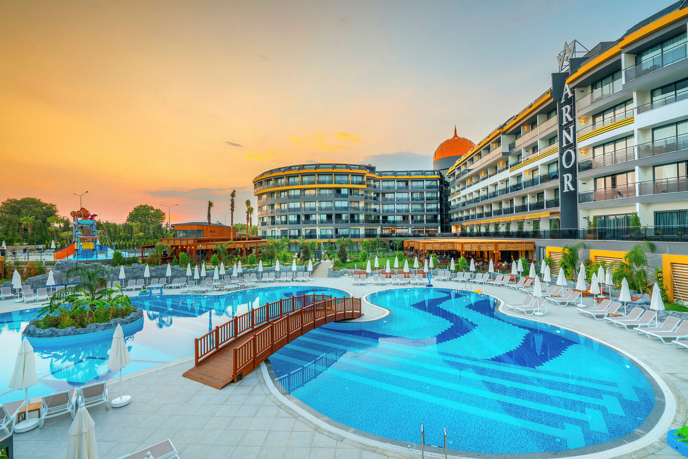 En utomhuspool med solstolar och parasoller bredvid ett hotell. (AI-genererad text)