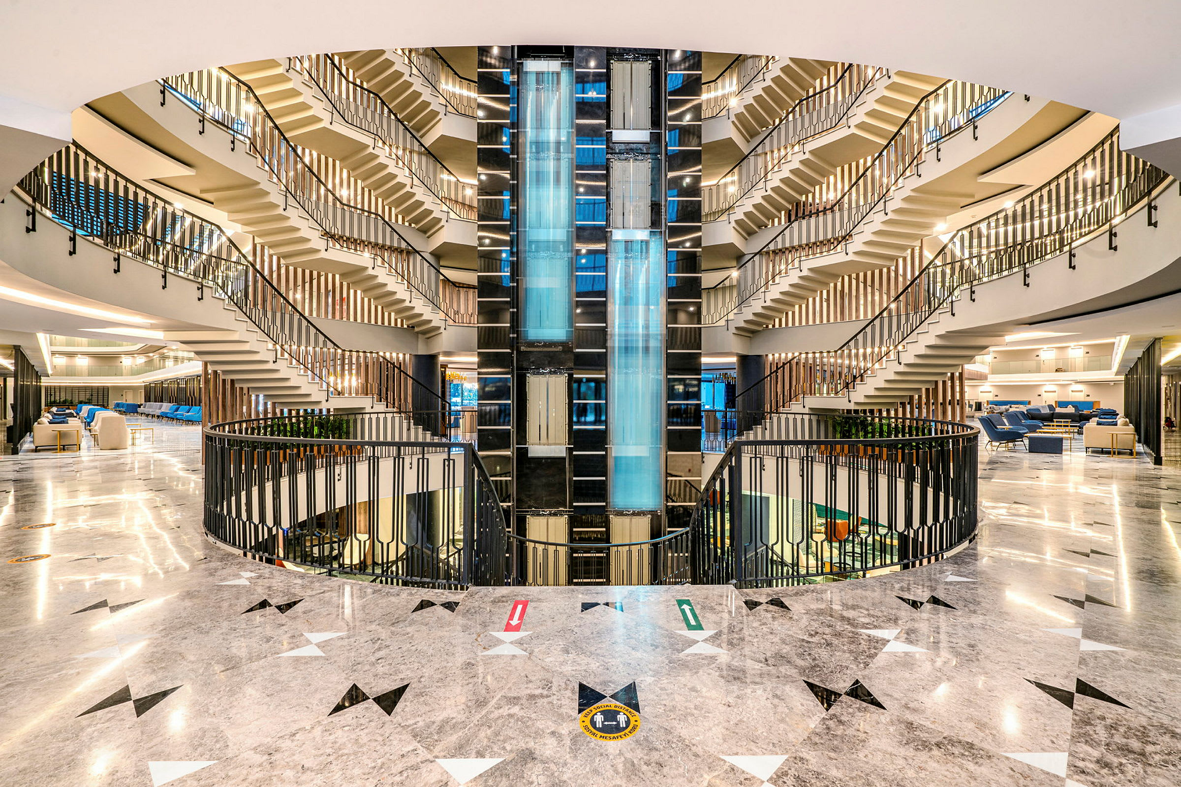 Hotellets atrium med ljusdesign, glas hissar och trappor som leder uppåt. (AI-genererad text)