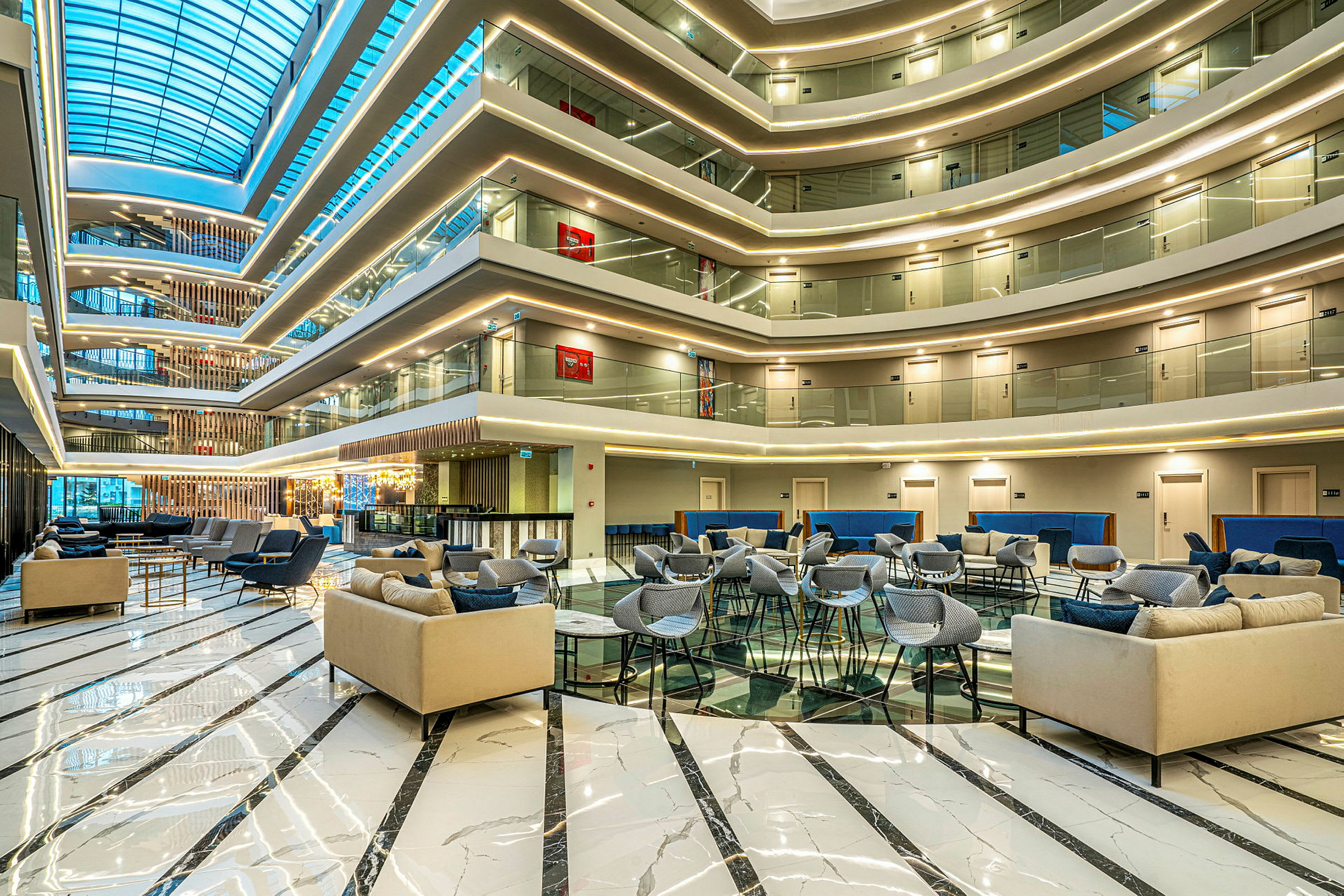 Moderna loungemöbler i en rymlig hotellobby med ett tak av glas. (AI-genererad text)