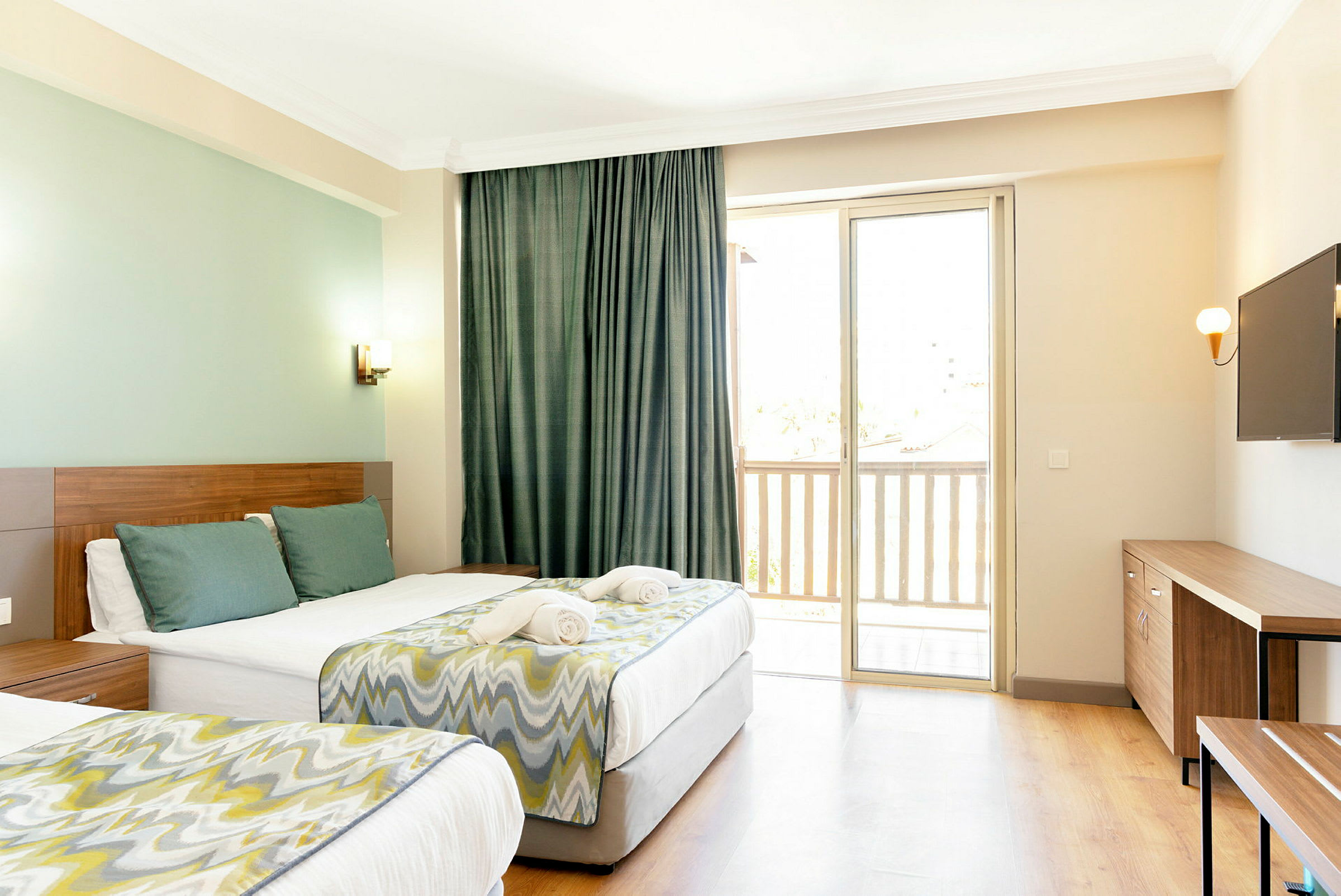 Ett hotellrum med två sängar, en TV på väggen och ett fönster med balkong. (AI-genererad text)