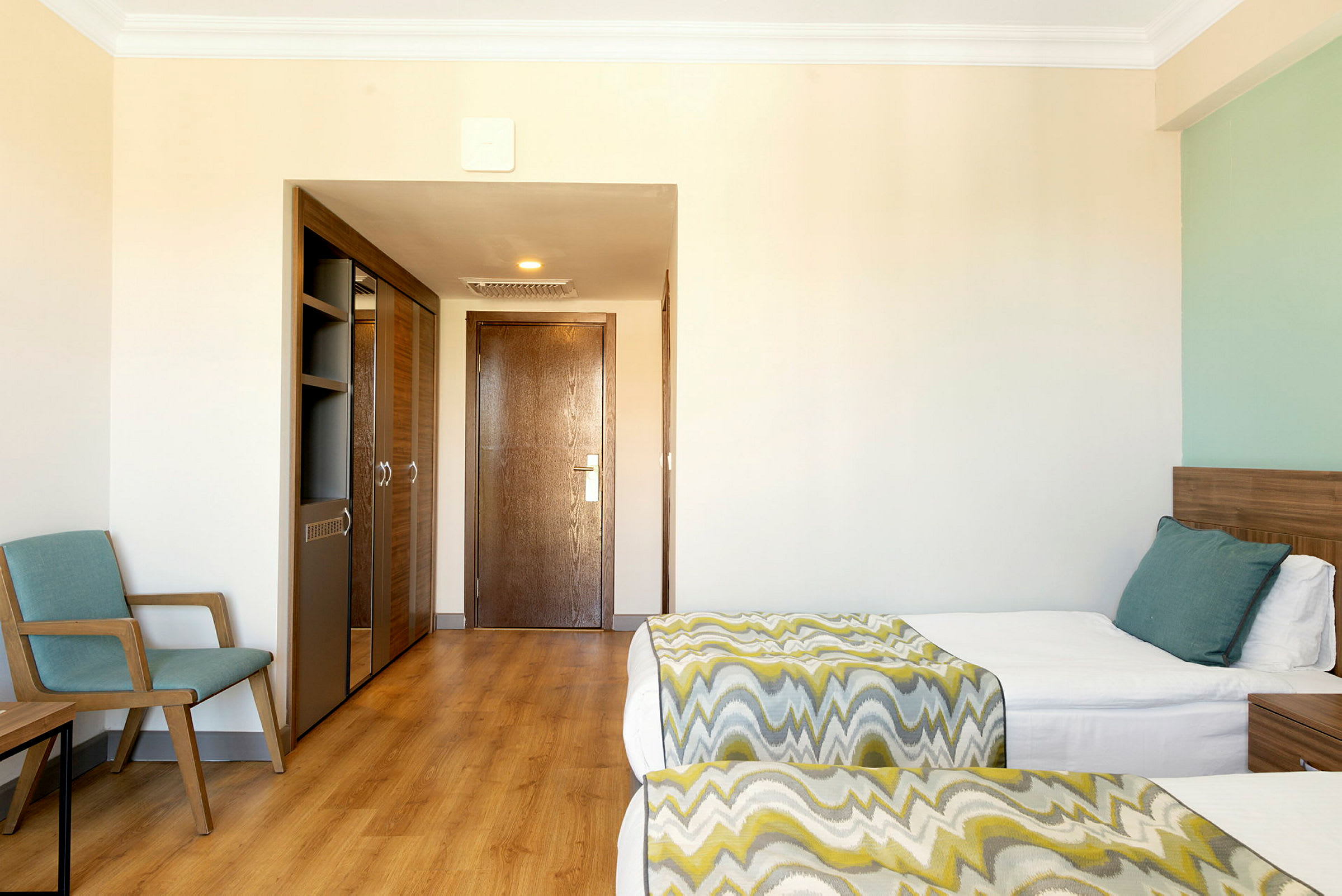Ett hotellrum med två sängar, en stol och en garderob. (AI-genererad text)