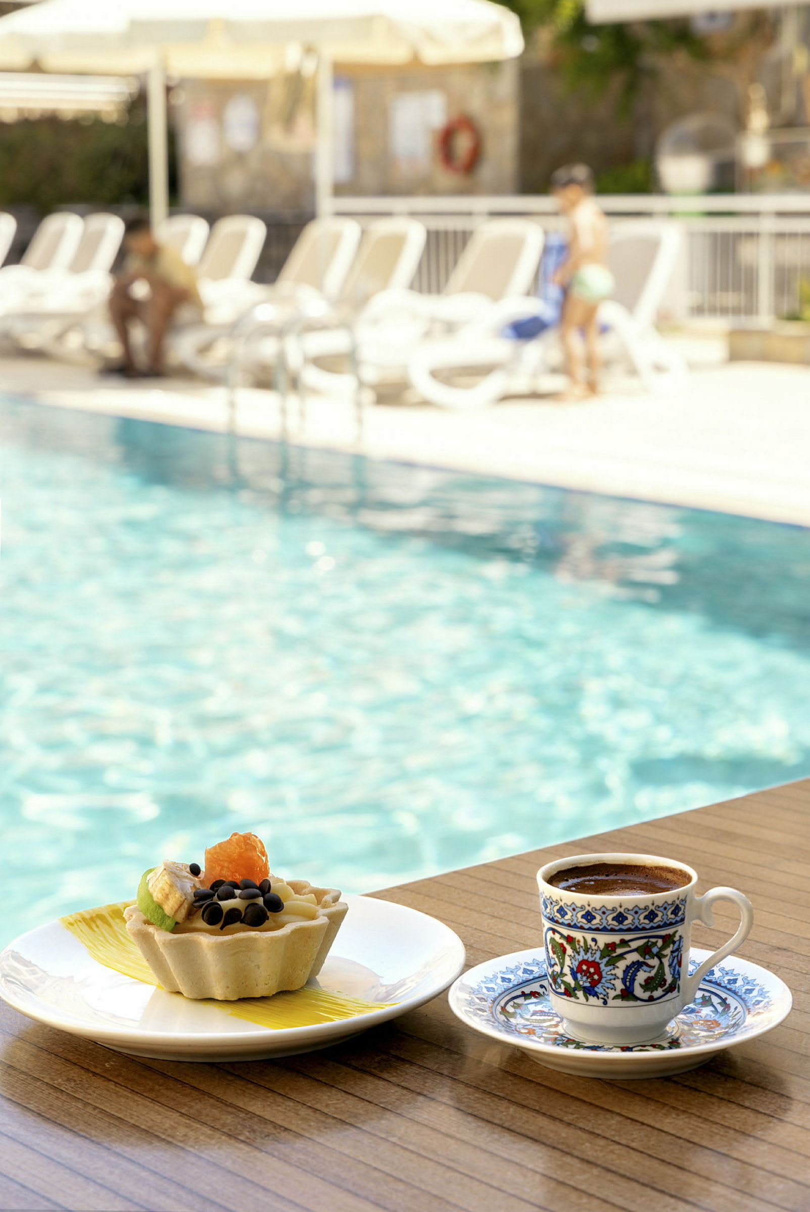 En kopp kaffe och en dessert vid kanten av en pool. (AI-genererad text)