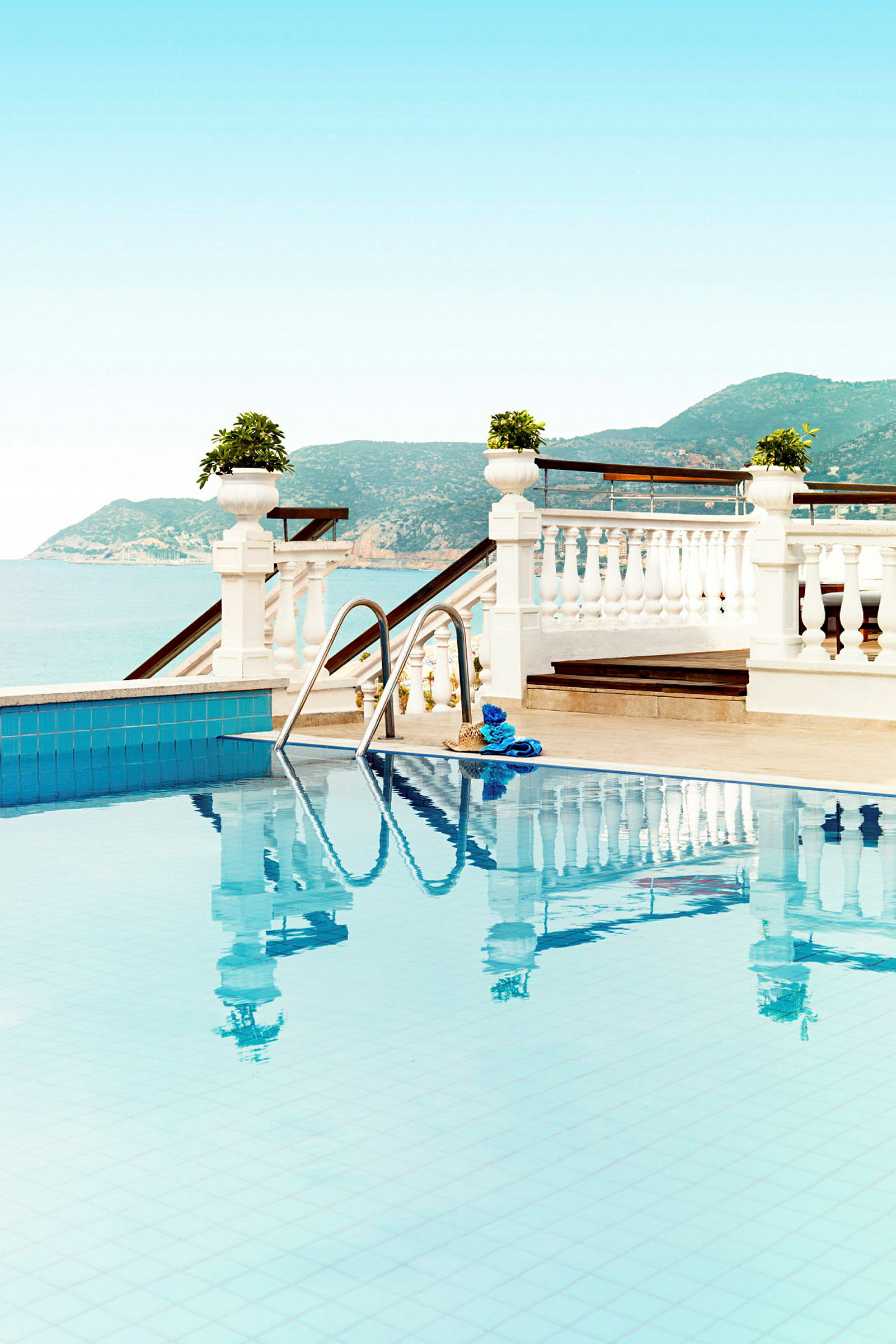 Pool med utsikt över havet och omgivande kullar. (AI-genererad text)