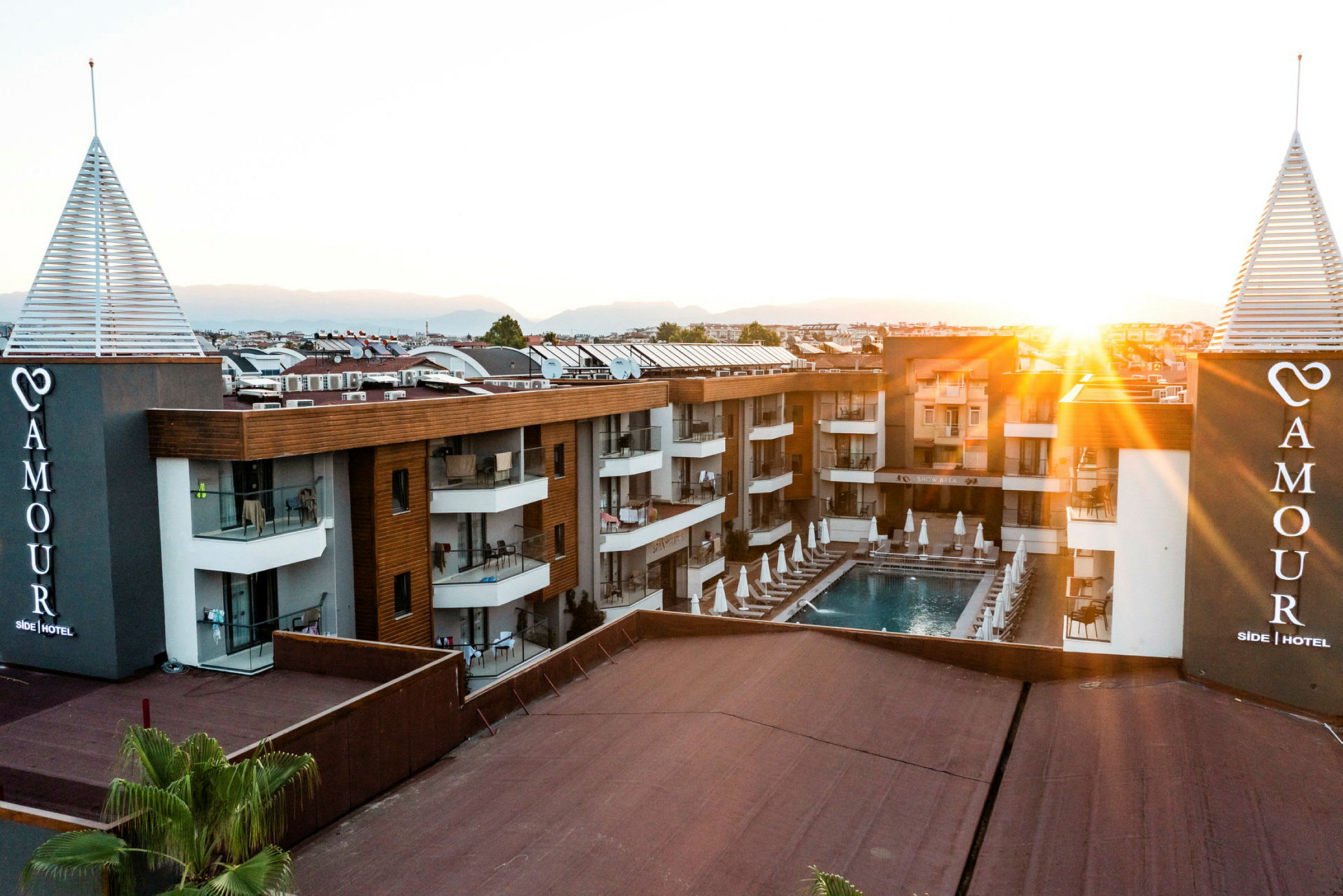 Hotellbyggnad med pool och solstolar vid solnedgång. (AI-genererad text)