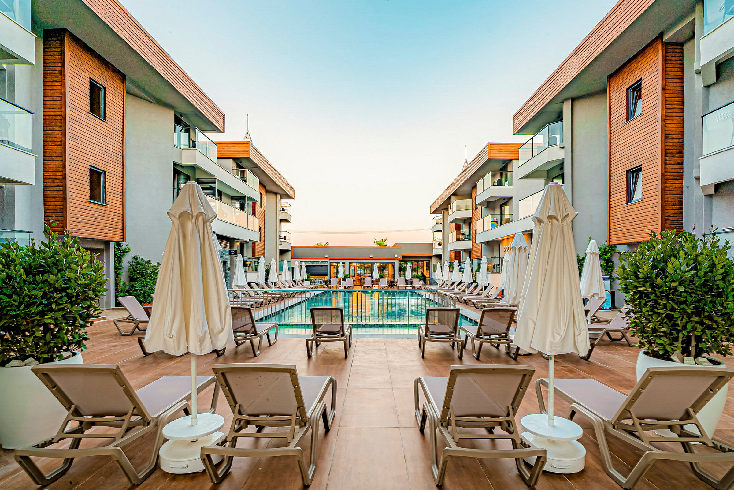 Hotellområde med en pool och solstolar omgivna av byggnader. (AI-genererad text)