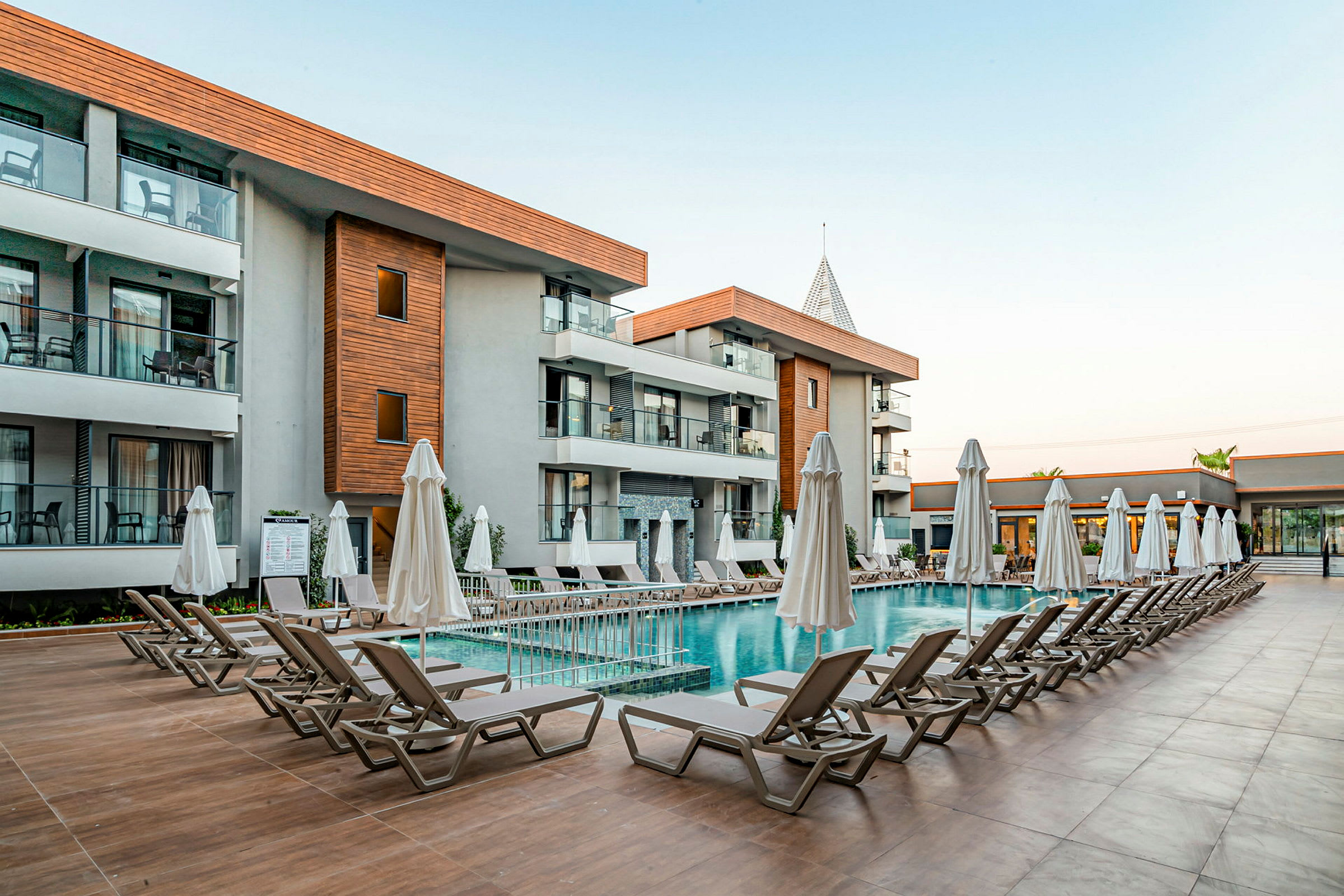 Exteriör av ett hotell med en pool och solstolar. (AI-genererad text)