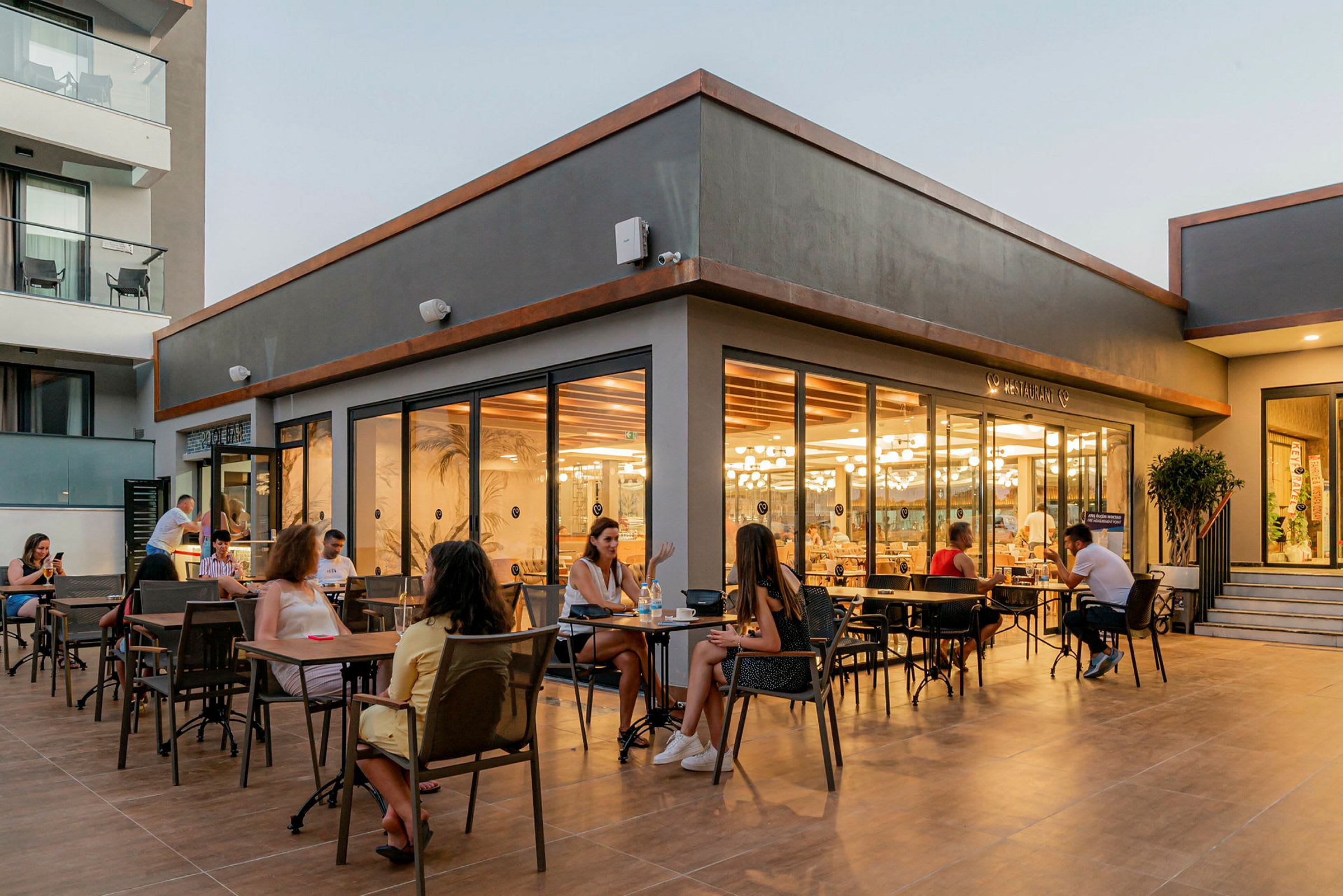 Uteservering med matgäster vid ett modernt restaurangområde. (AI-genererad text)
