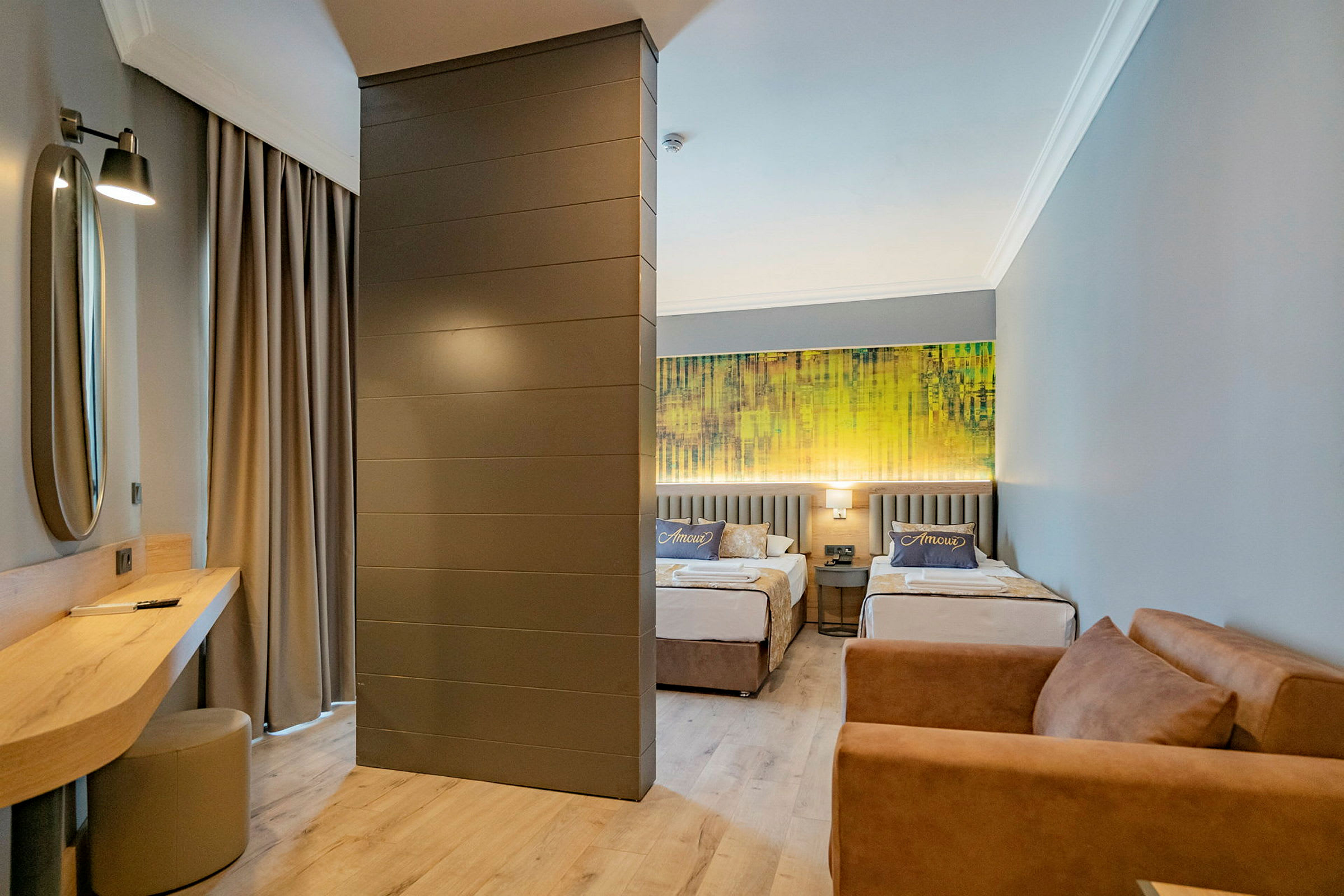 Hotellrum med två enkelsängar, en soffa och ett skrivbord. (AI-genererad text)