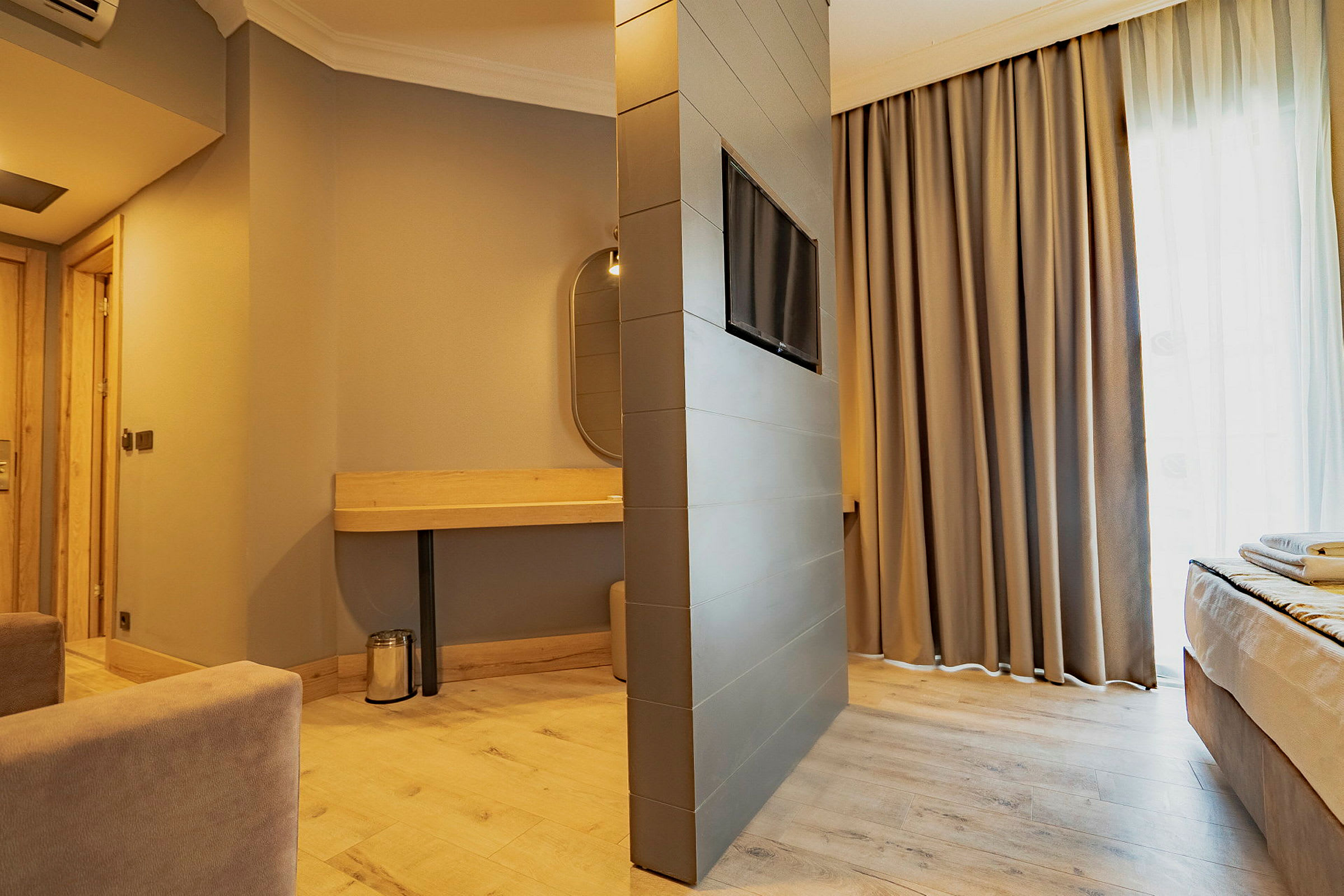 Modernt hotellrum med varm inredning, bekväma möbler och kombinerad soffa och sovområde. (AI-genererad text)
