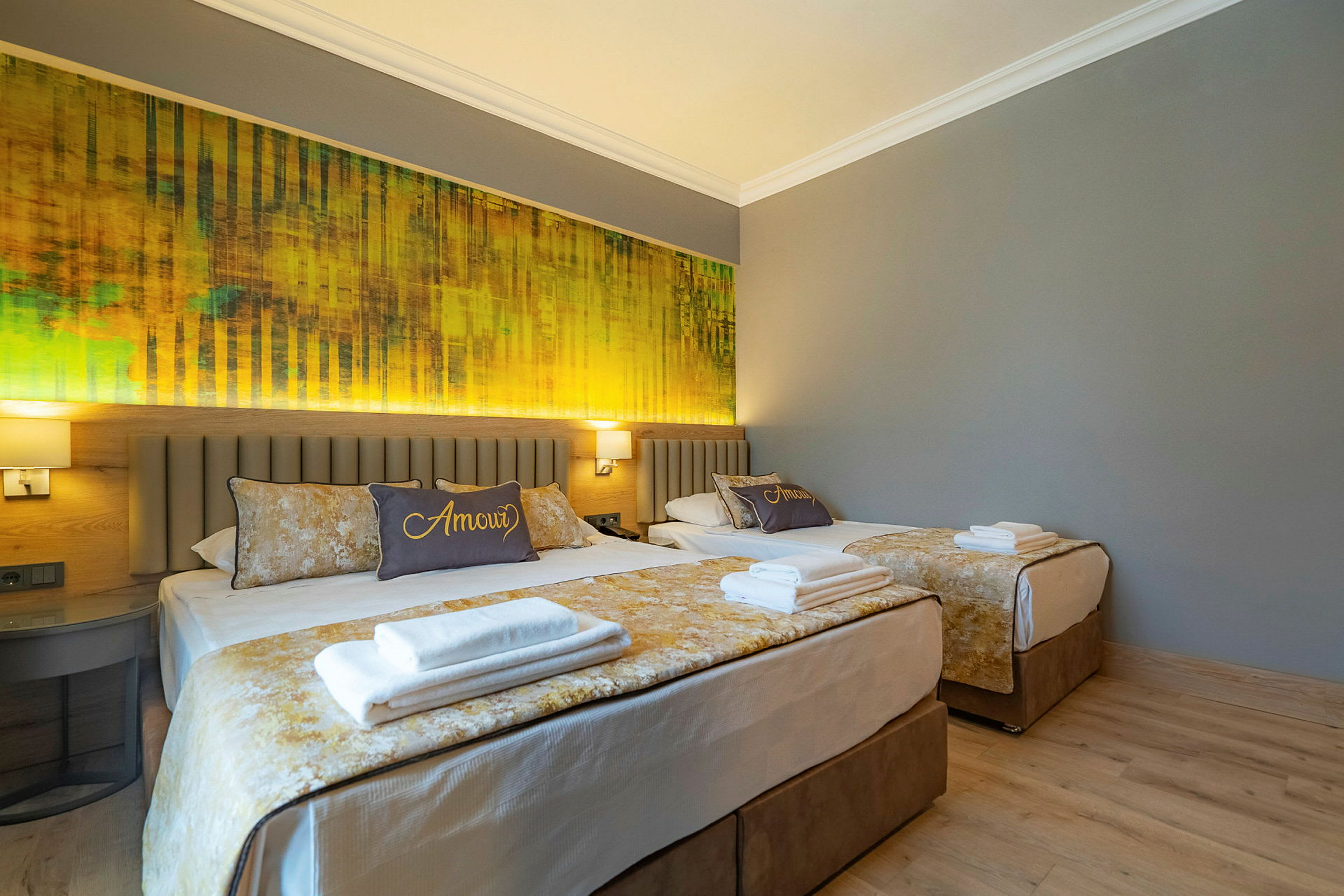Två sängar i ett hotellrum med grå väggar och gul inredning. (AI-genererad text)