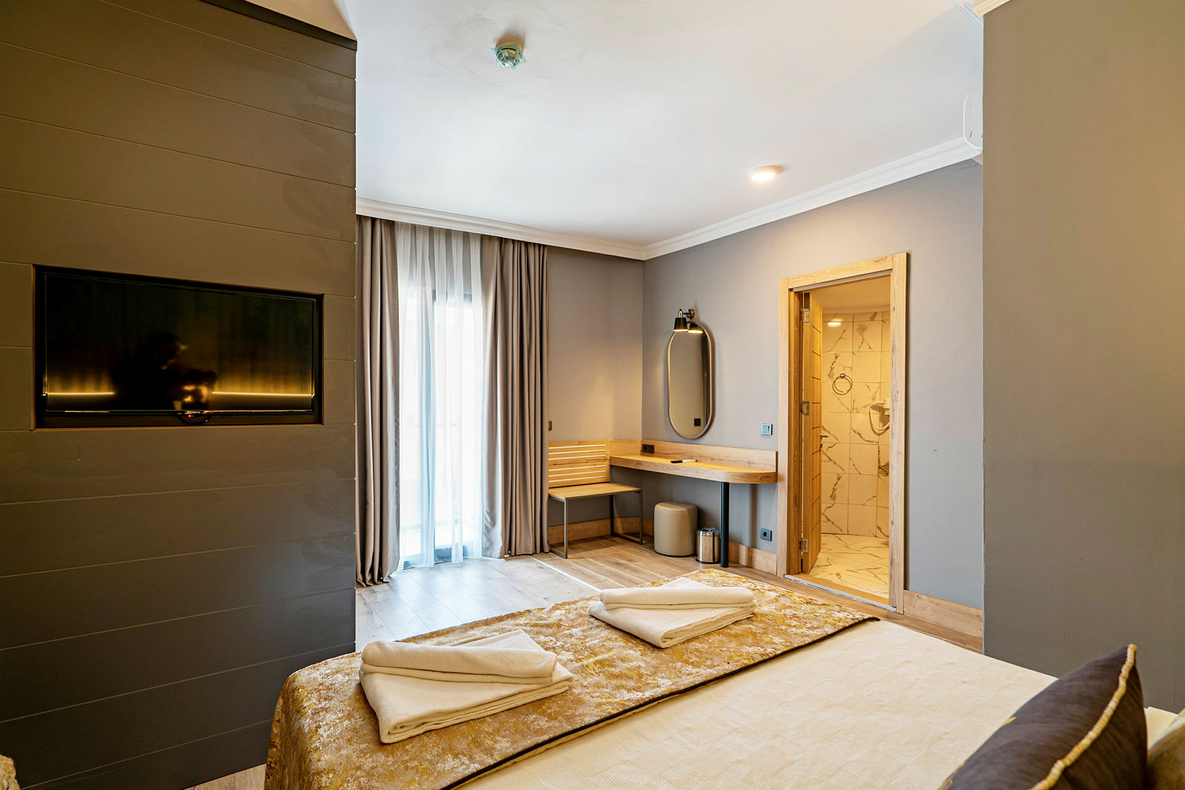 Hotellrum med dubbelsäng, TV på väggen, skrivbord, och banrum. (AI-genererad text)