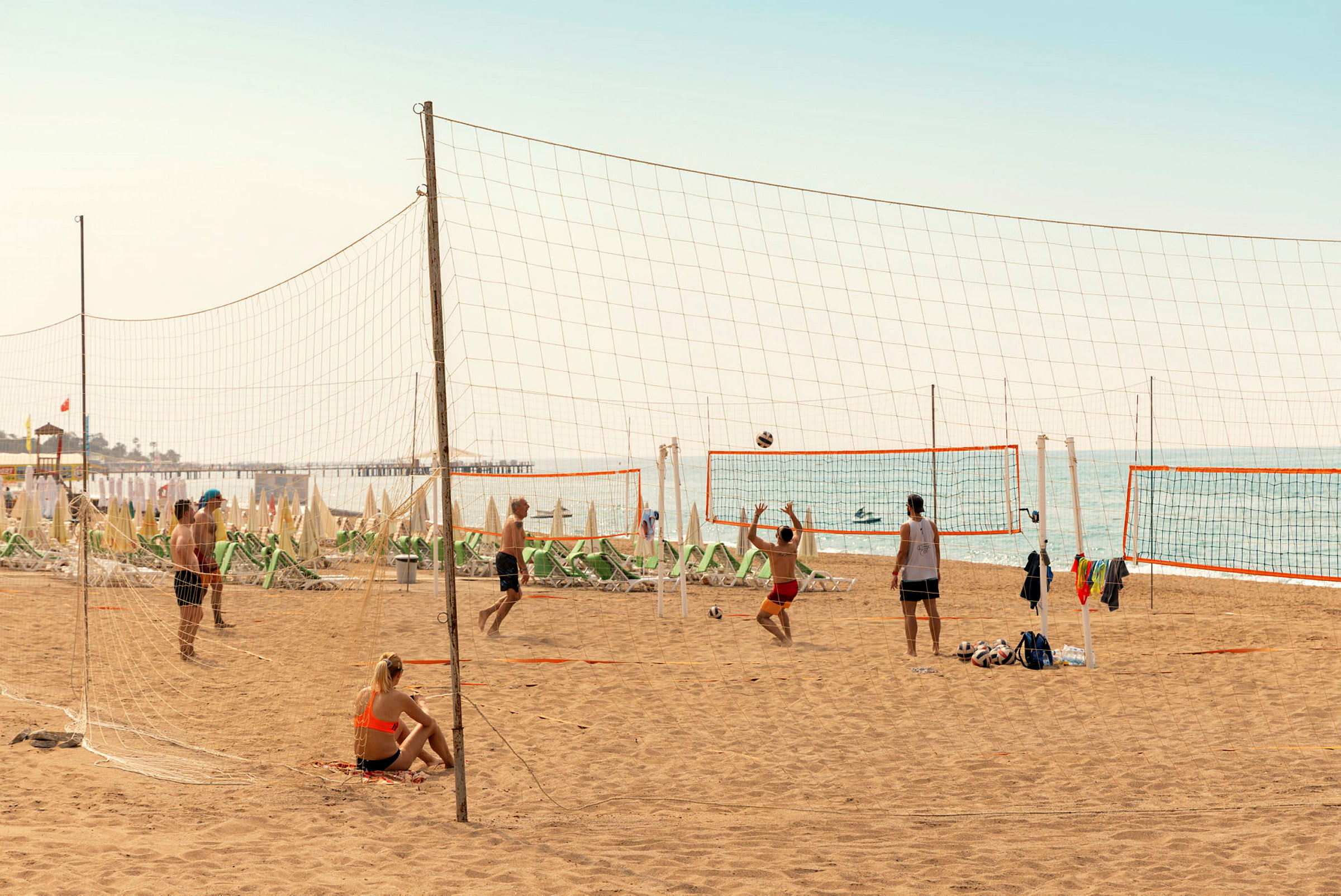 Personer spelar beachvolleyboll på en sandstrand vid havet. (AI-genererad text)