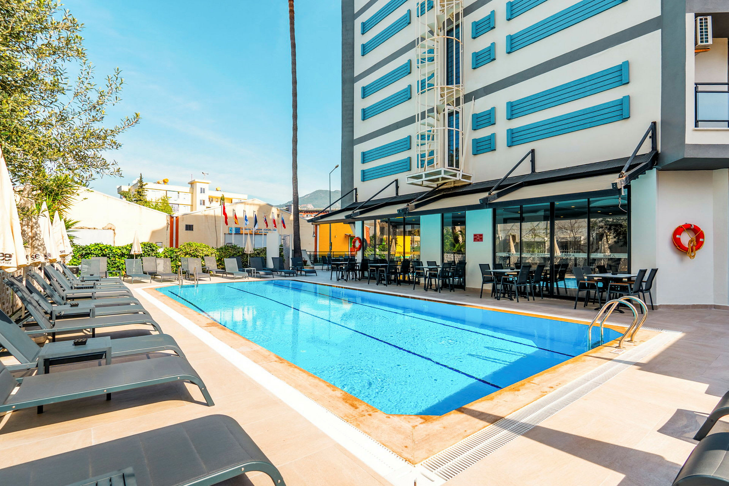 En utomhuspool med solstolar och ett hotell i bakgrunden. (AI-genererad text)