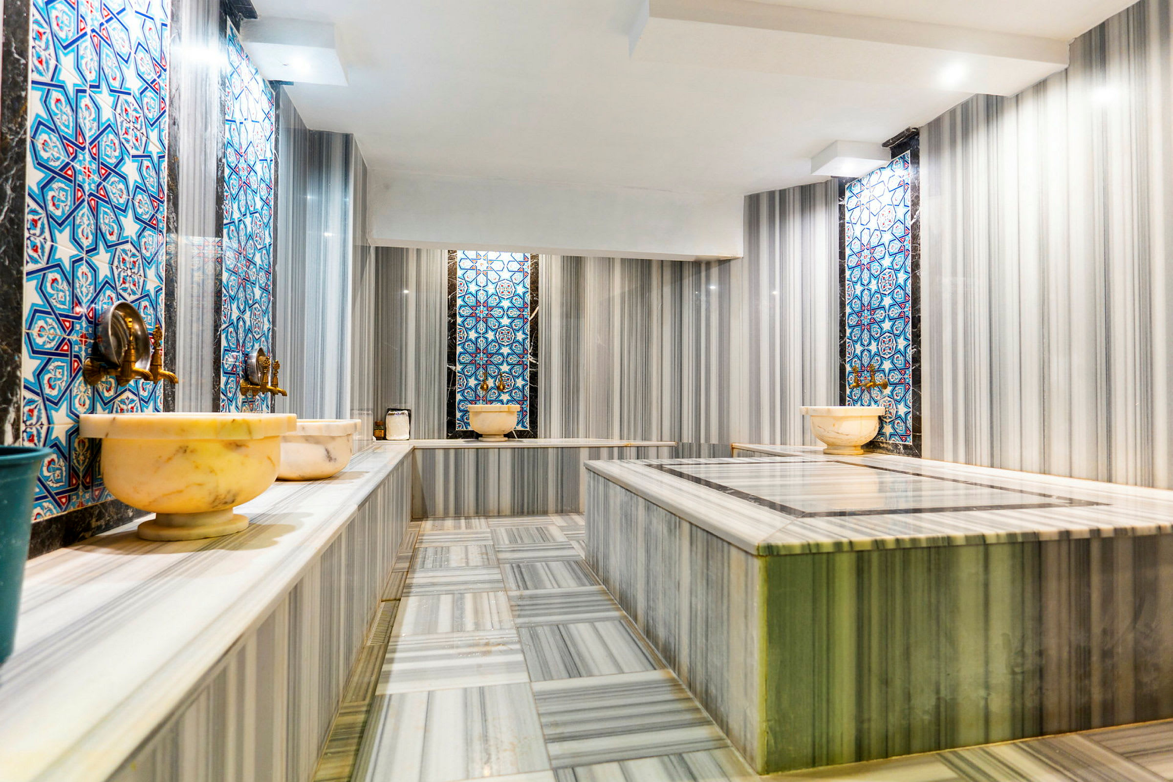 Ett hamam med marmorytor och färgglada mosaikpaneler. (AI-genererad text)