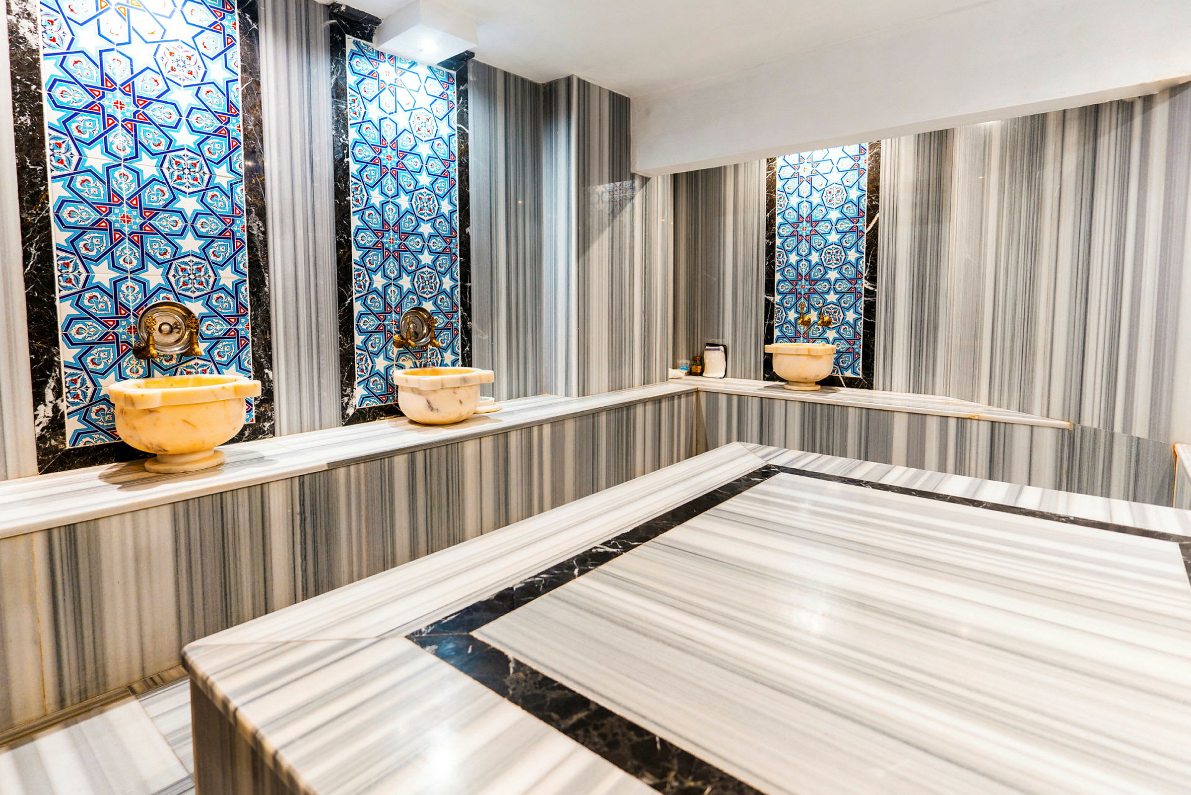 Traditionellt hamam med marmorytor och blå mosaik på väggarna. (AI-genererad text)