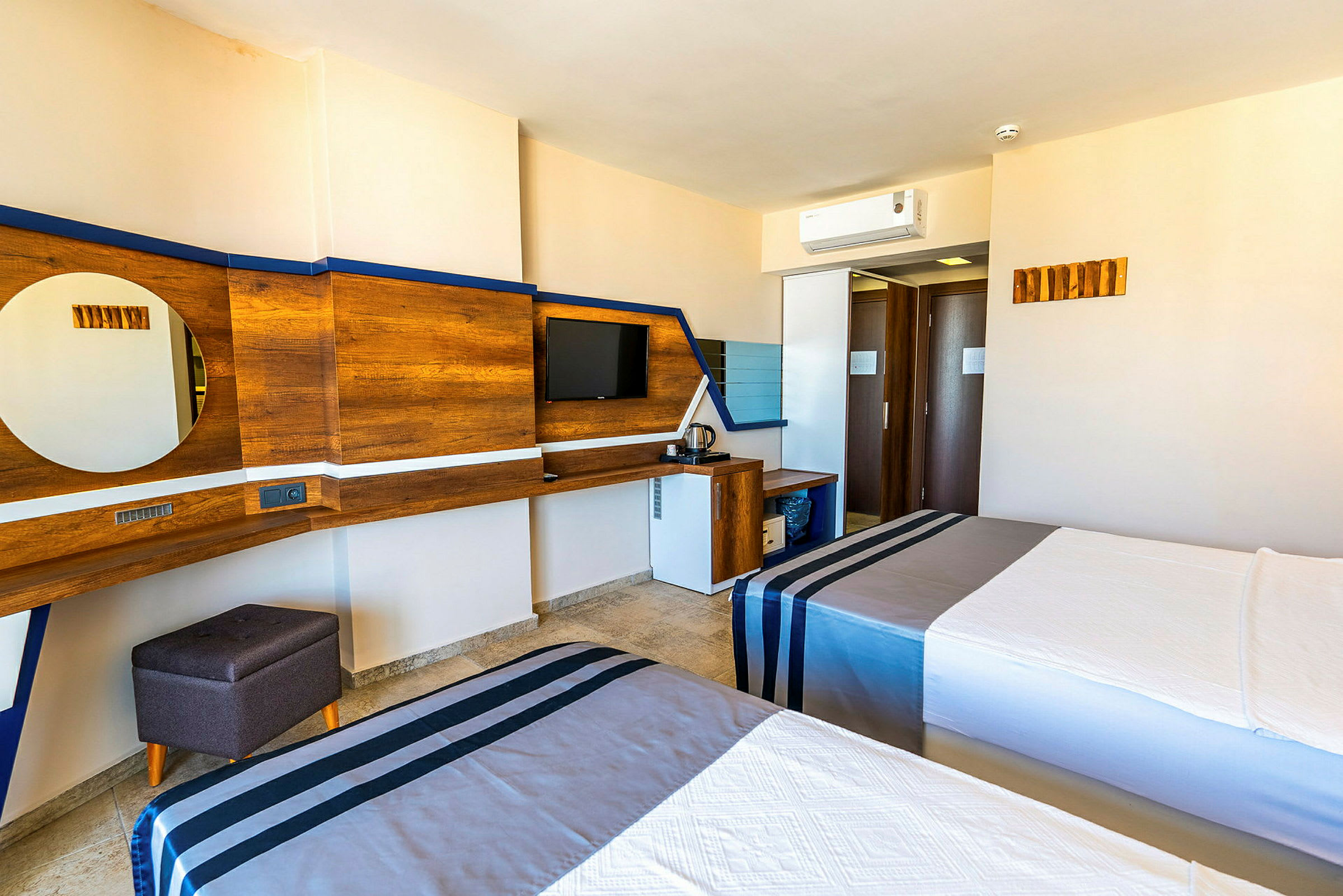 Hotellrum med två sängar, tv på väggen och skrivbord med spegel. (AI-genererad text)