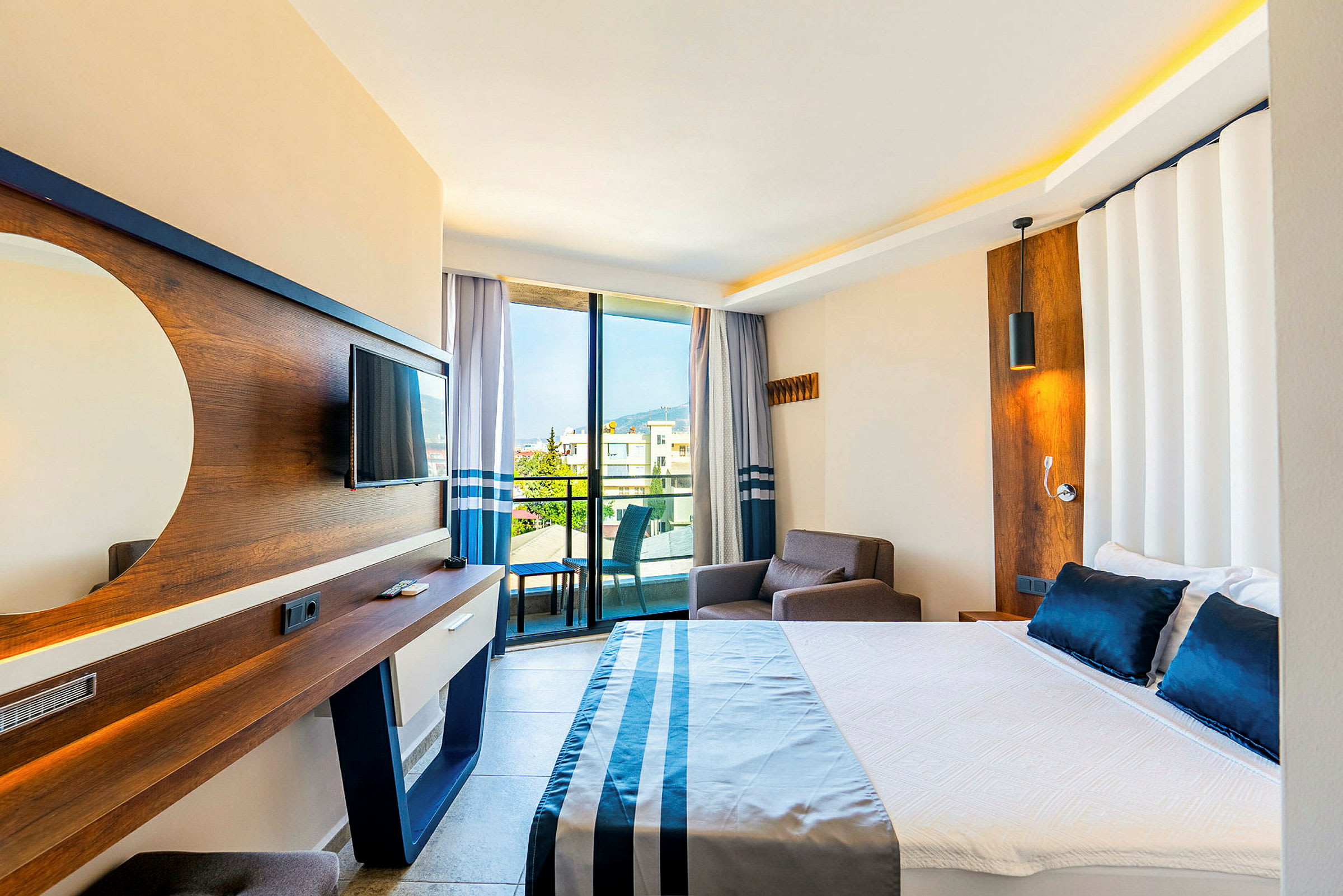 Hotellrum med säng, fåtölj, TV och balkong med utsikt. (AI-genererad text)