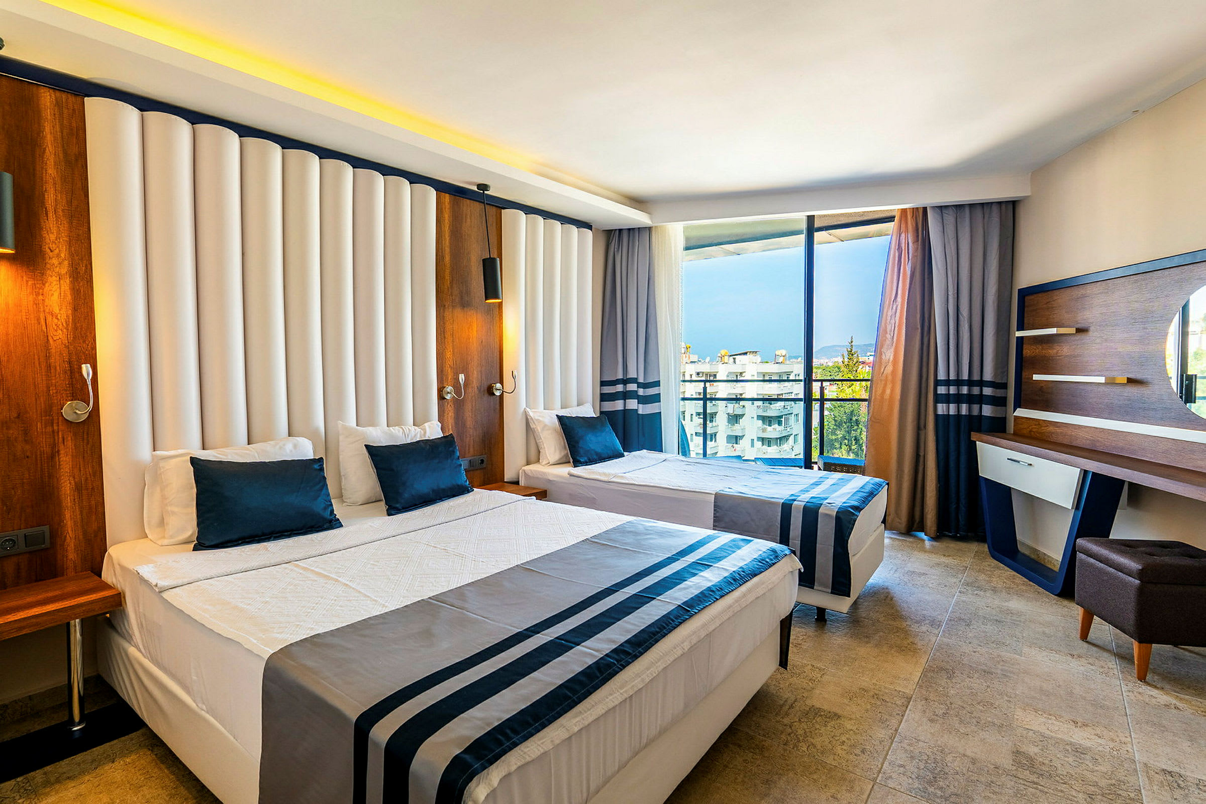 Hotellrum med två bäddar och modern inredning. Utsikt över byggnader och träd genom fönstret. (AI-genererad text)