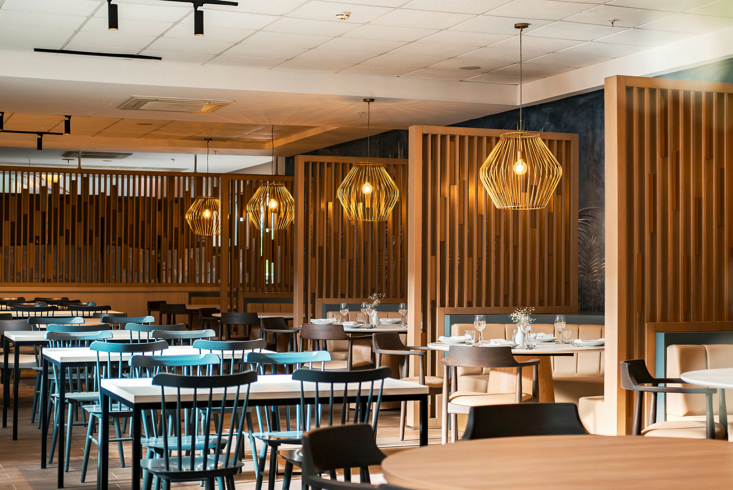 En restaurang med flera bord och stolar samt dekorativa lampor. (AI-genererad text)