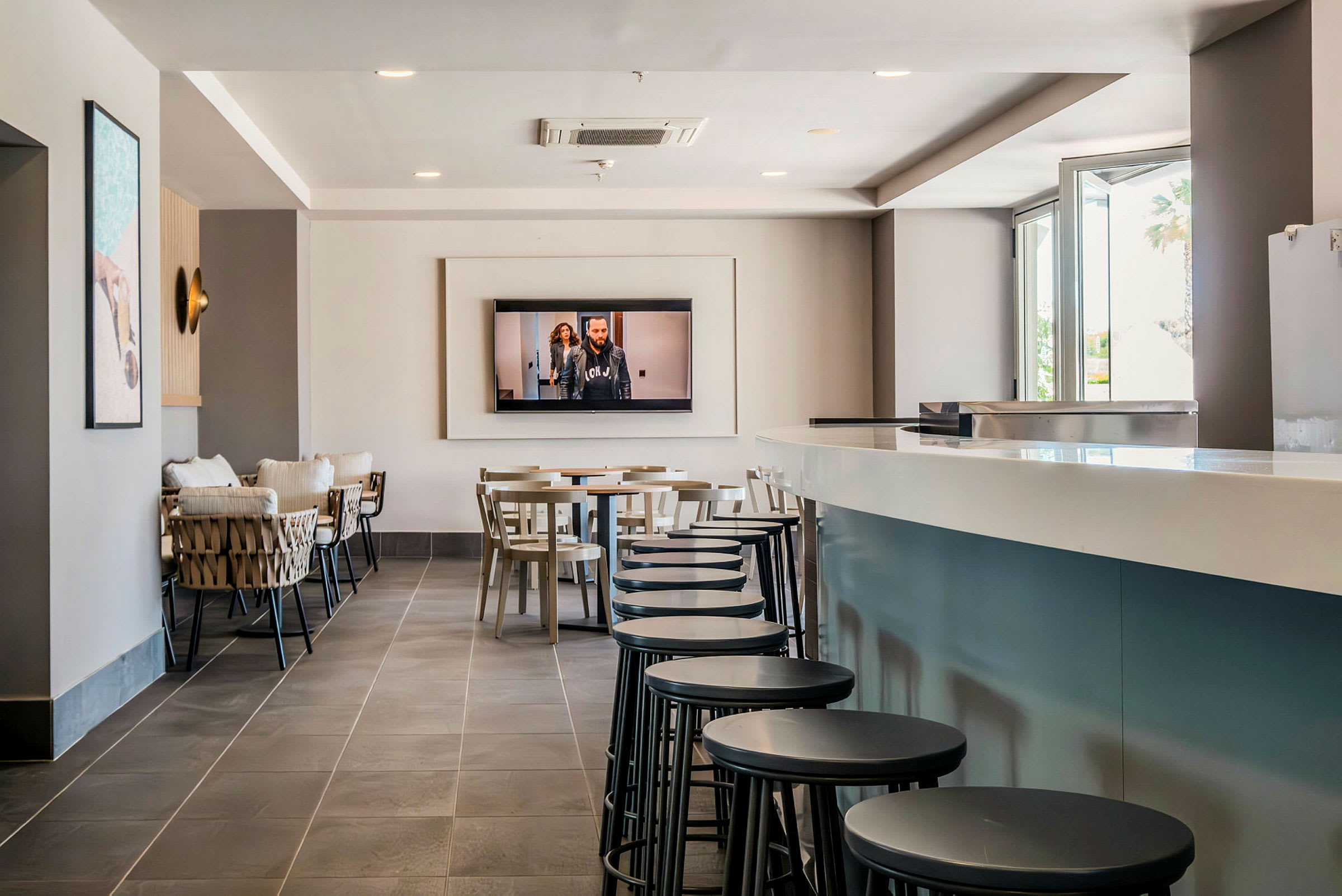 En modern lounge med sittplatser, en TV på väggen och en lång bardisk. (AI-genererad text)