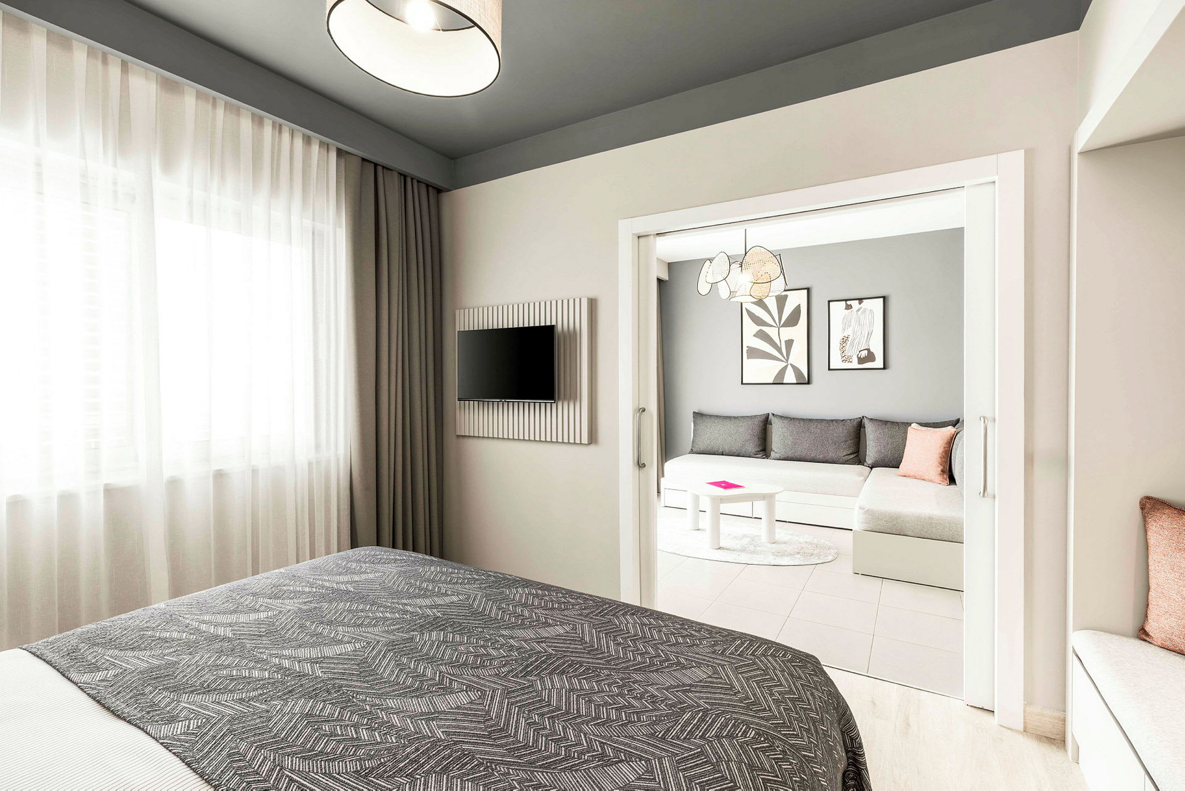 Hotellrum med en säng i förgrunden, en TV på väggen och en separat sittgrupp med soffa och bord. (AI-genererad text)