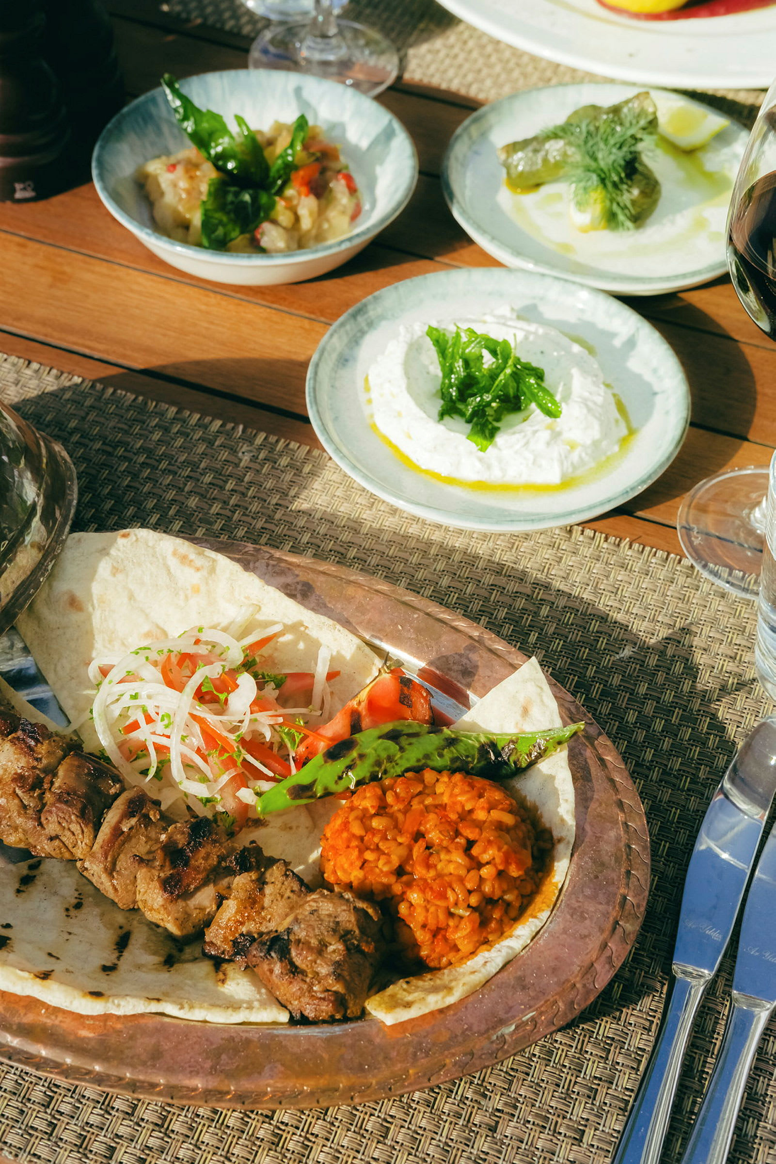 Tallrik med grillat kött, grönsaker och bönor med såser i bakgrunden. (AI-genererad text)