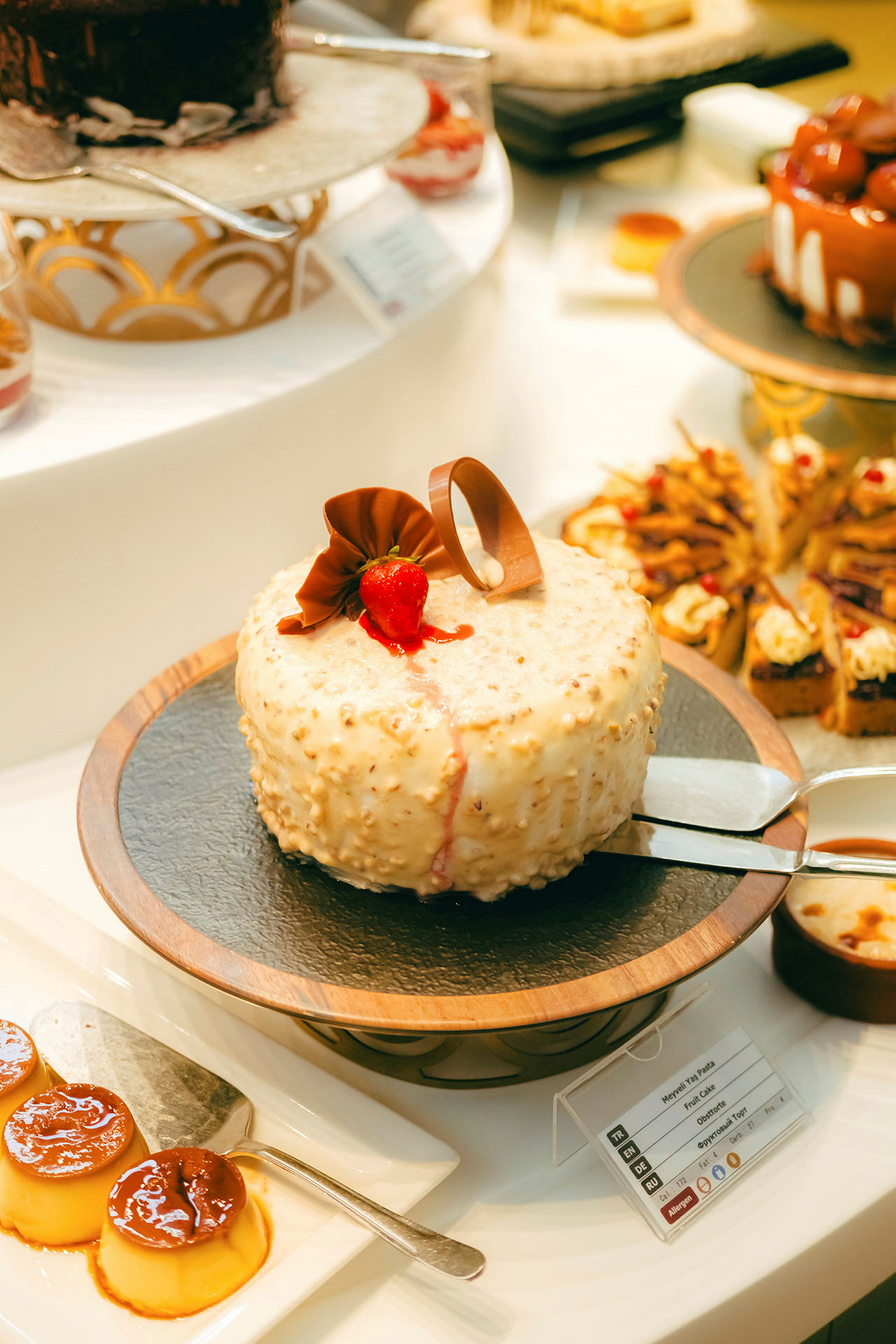 En dessertbuffé med olika bakverk, inklusive en gräddtårta med chokladdekoration och jordgubbe. (AI-genererad text)