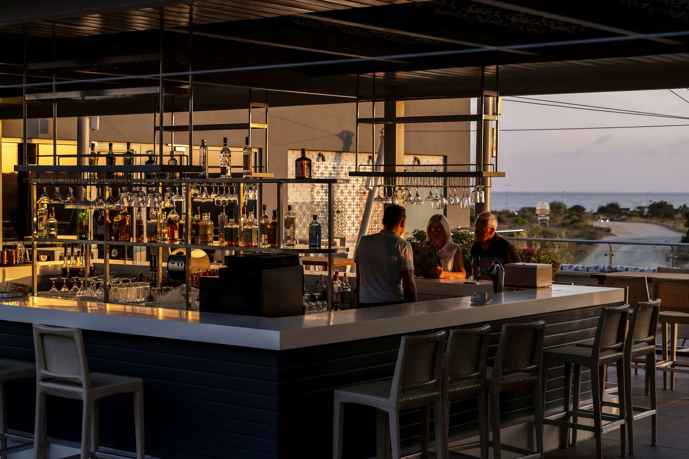 Vy över en modern bar med sittplatser och utsikt över landskap och hav. (AI-genererad text)