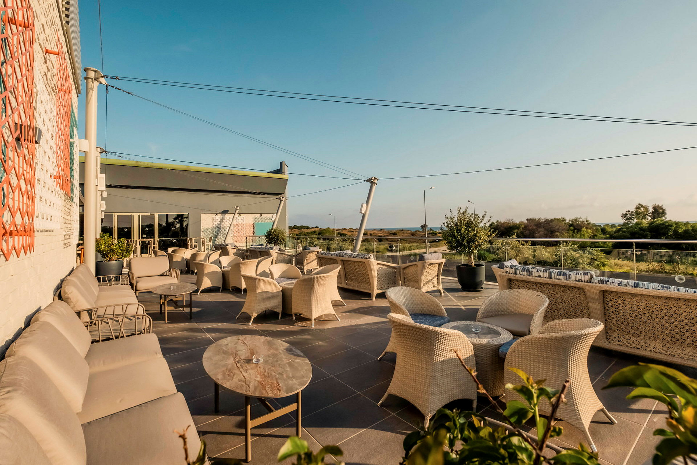 En utomhusterrass med flera soffor och stolar, omgiven av grönska och med utsikt mot havet. (AI-genererad text)