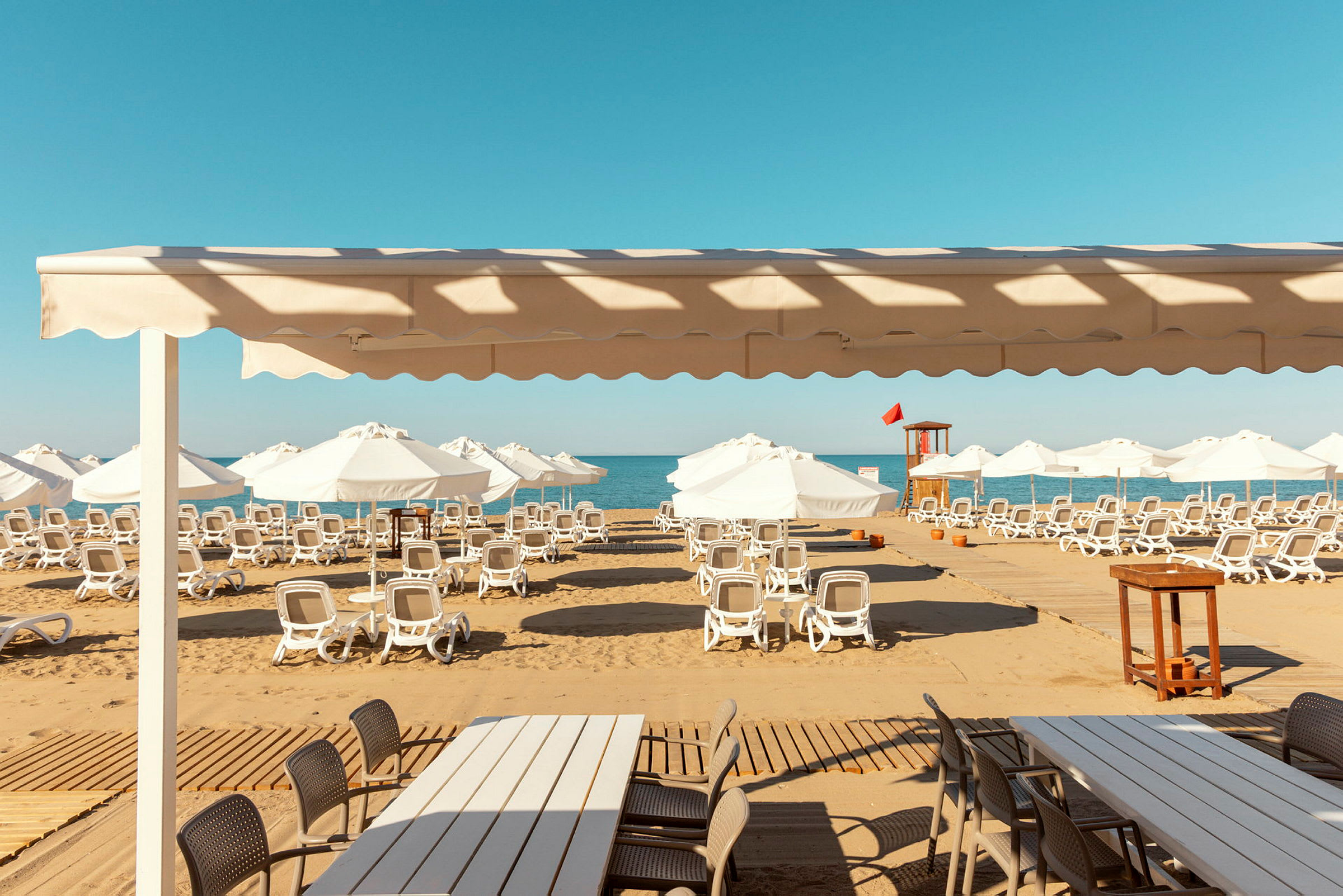 Solstolar och parasoller på en sandstrand med utsikt över havet. (AI-genererad text)