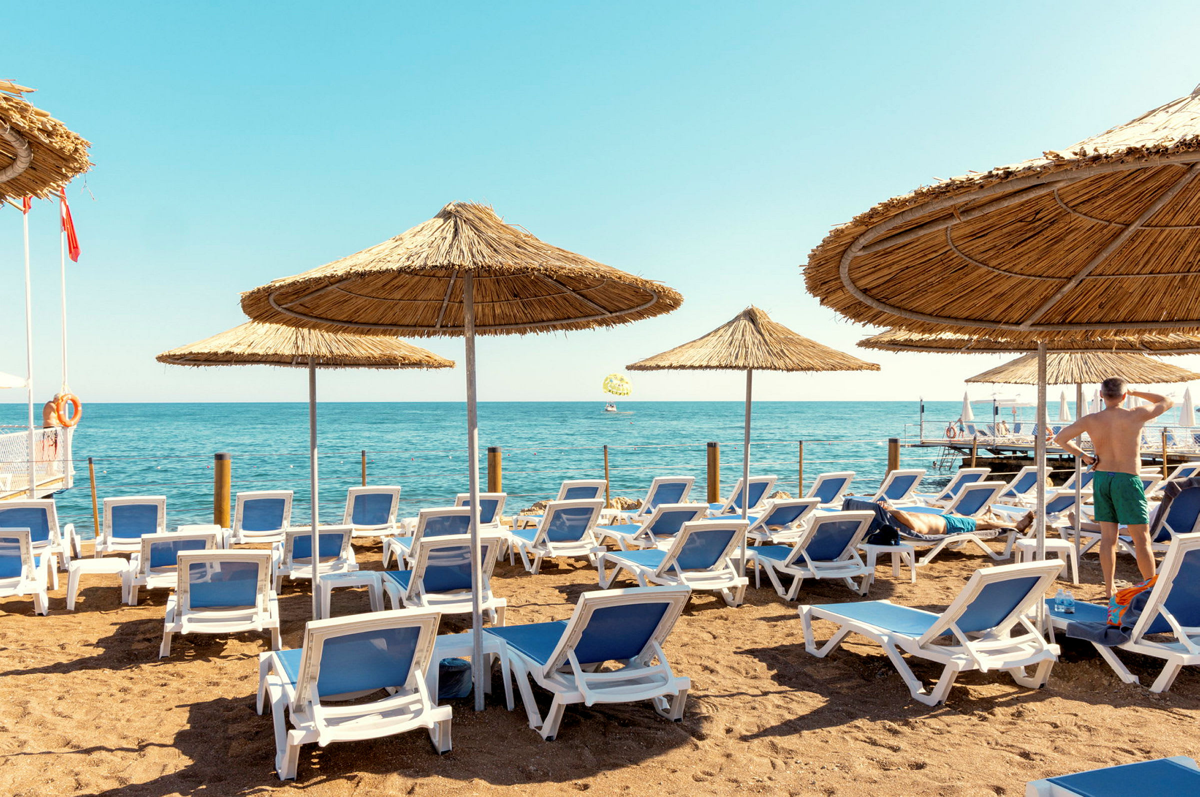 Strand med solstolar och parasoller, havet i bakgrunden. (AI-genererad text)