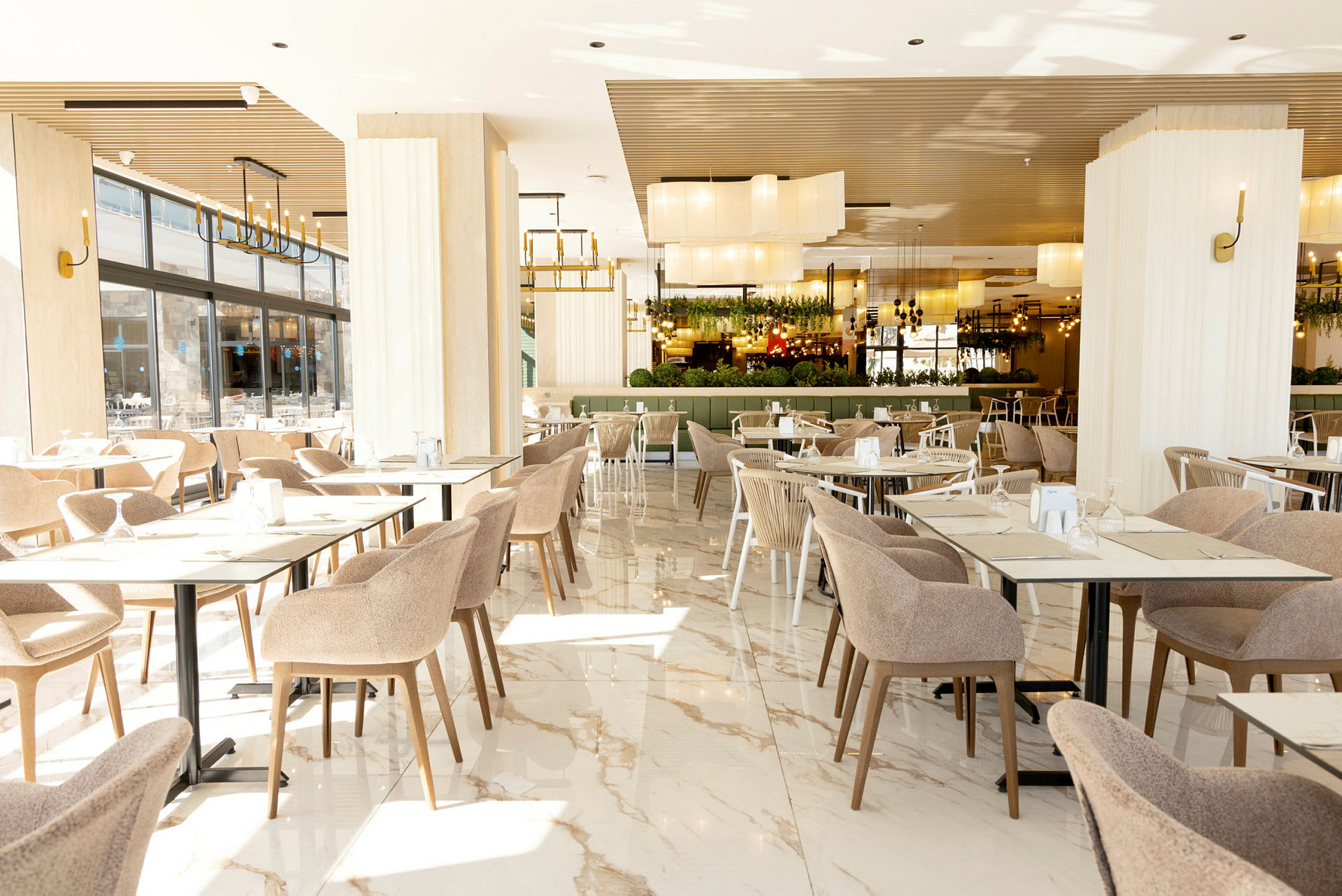 Interiör av en rymlig och ljus restaurang med bord och stolar. (AI-genererad text)