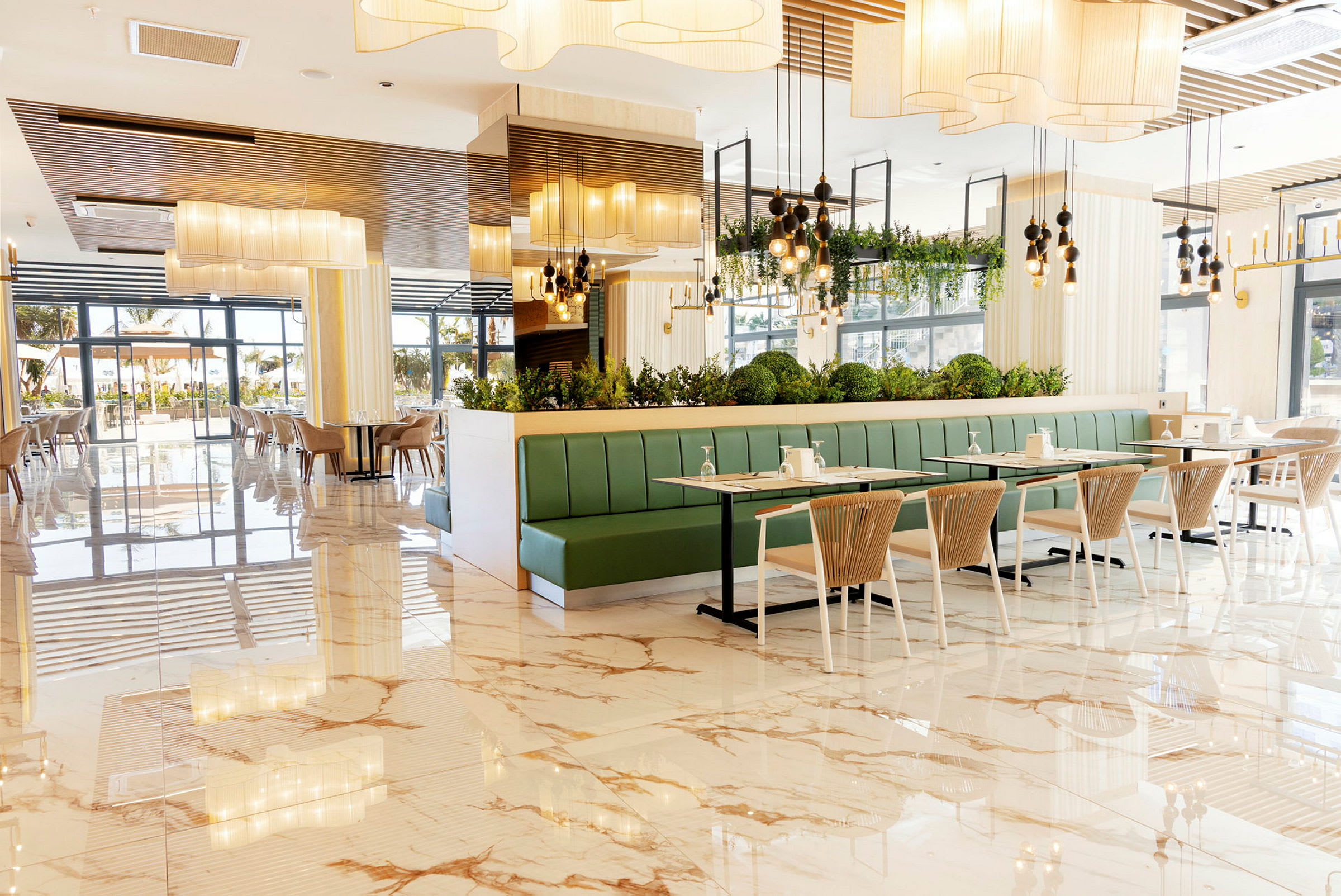 En ljus restaurang med marmorgolv, gröna sittbänkar och modernt inredda bord och stolar. (AI-genererad text)