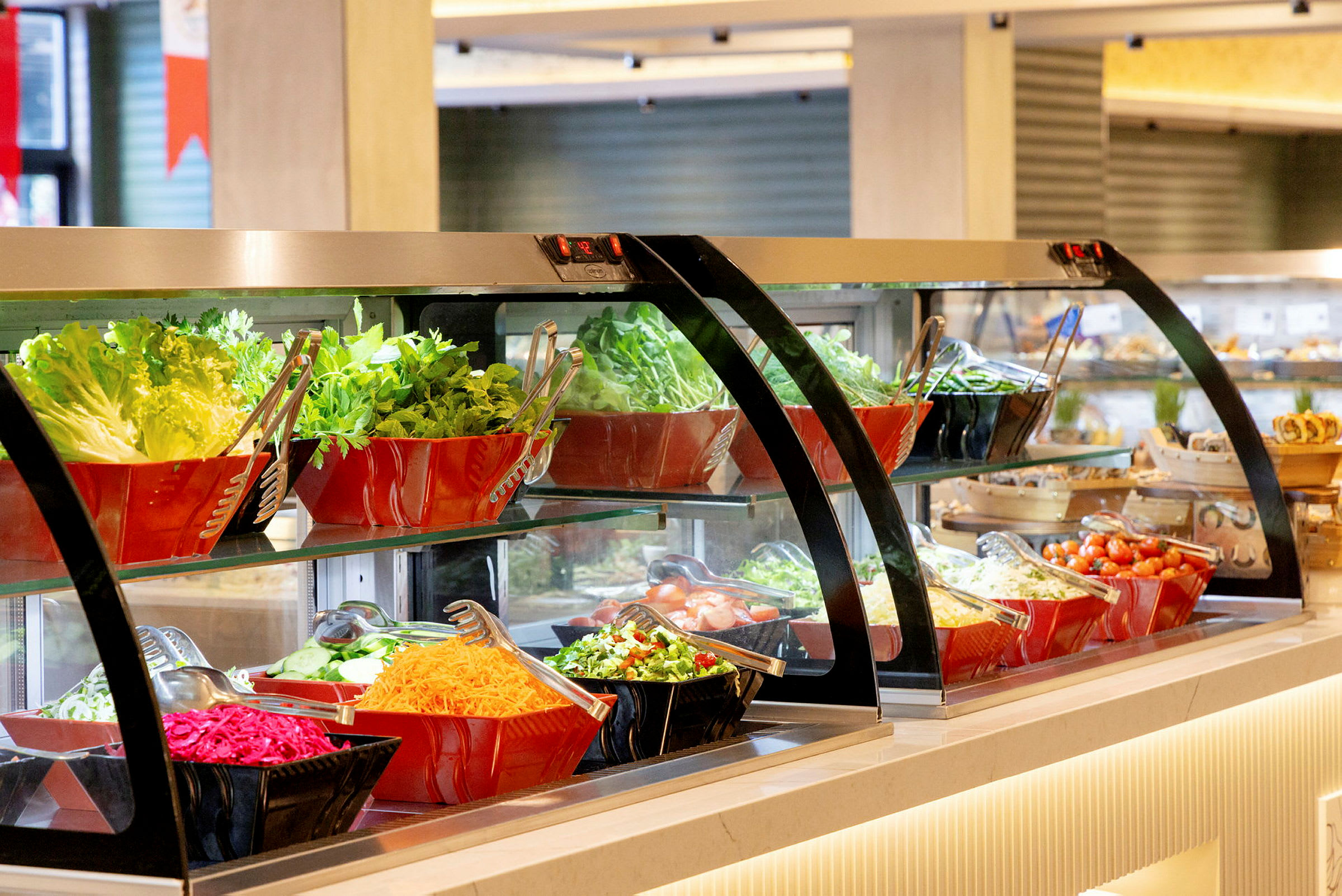 En salladsbuffé med olika grönsaker och salladsingredienser, arrangerade i skålar av glas och plast. (AI-genererad text)