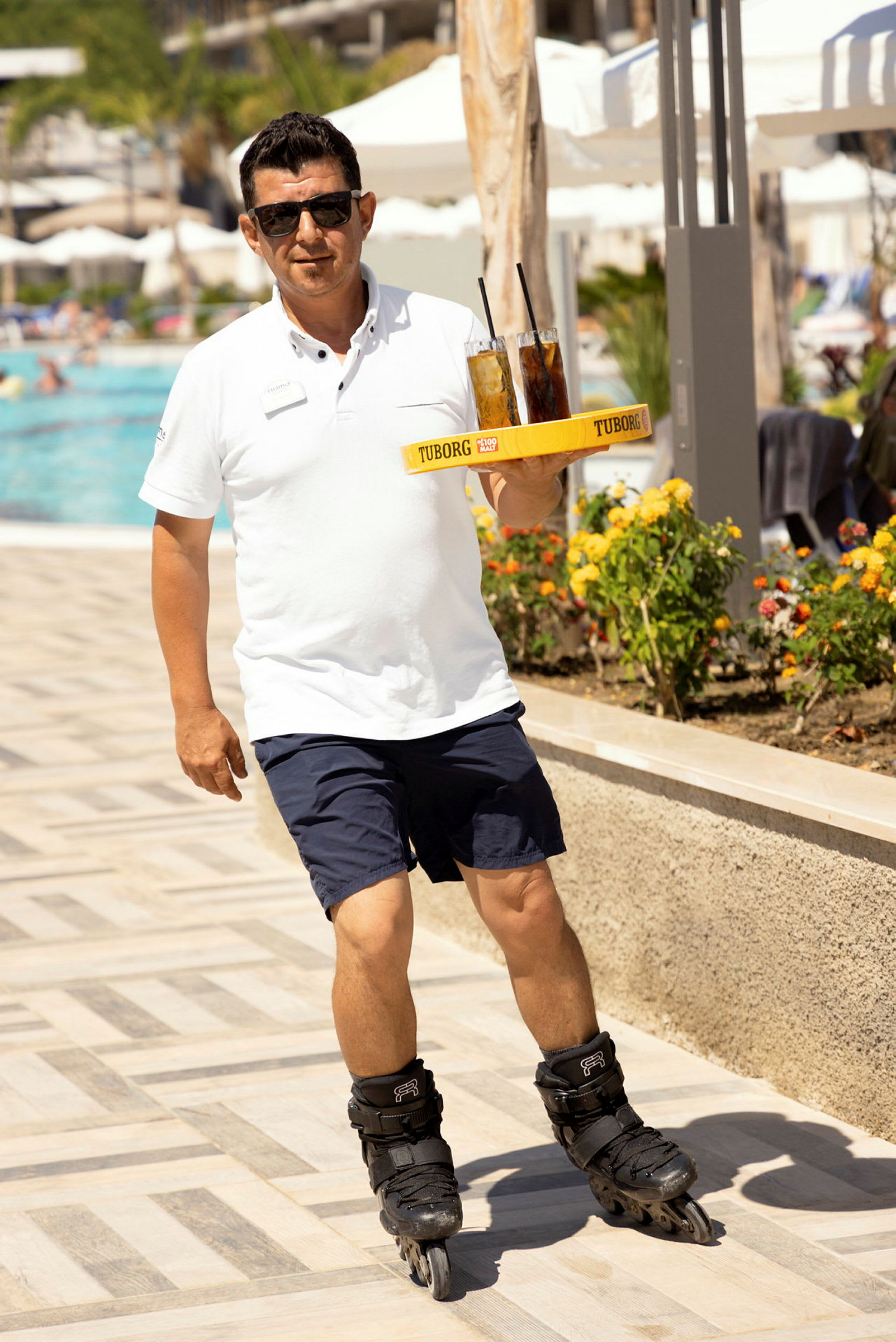 En person som bär rullskridskor serverar drycker vid en pool. (AI-genererad text)