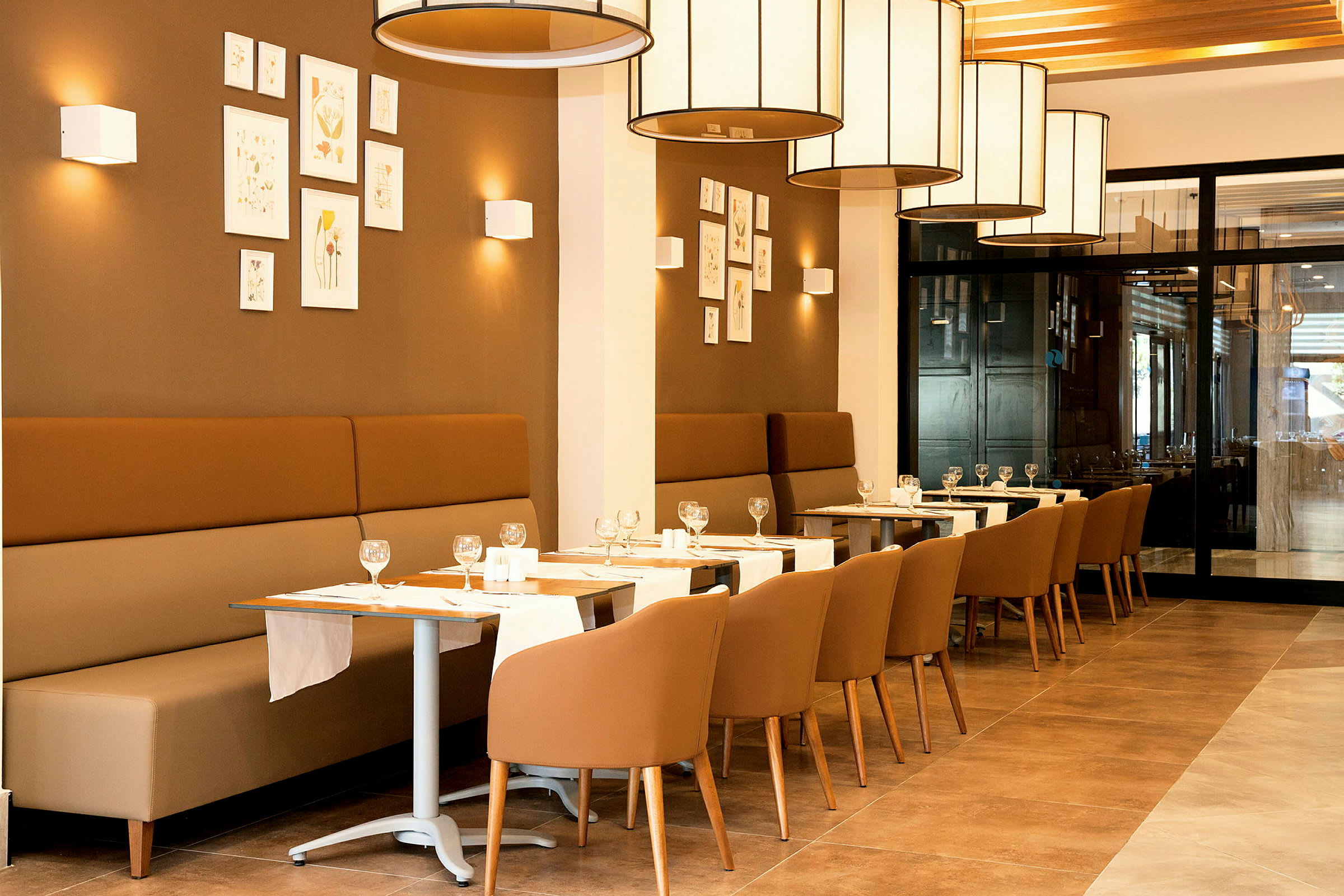 En restaurang med sittplatser, bord dukade med glas och servetter. (AI-genererad text)