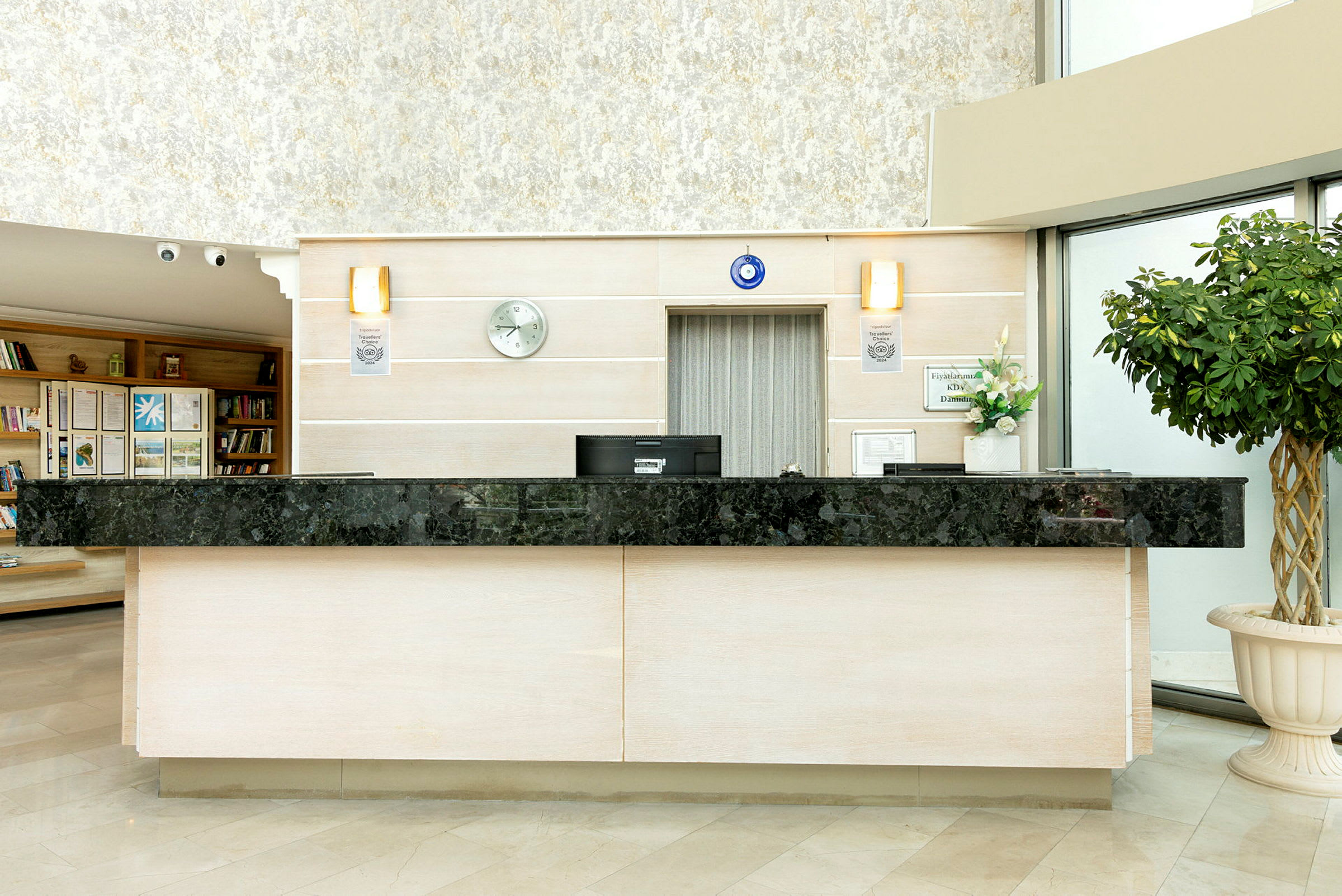Hotellreception med svart marmorbänkskiva, beige väggar och en grön växt till höger. (AI-genererad text)
