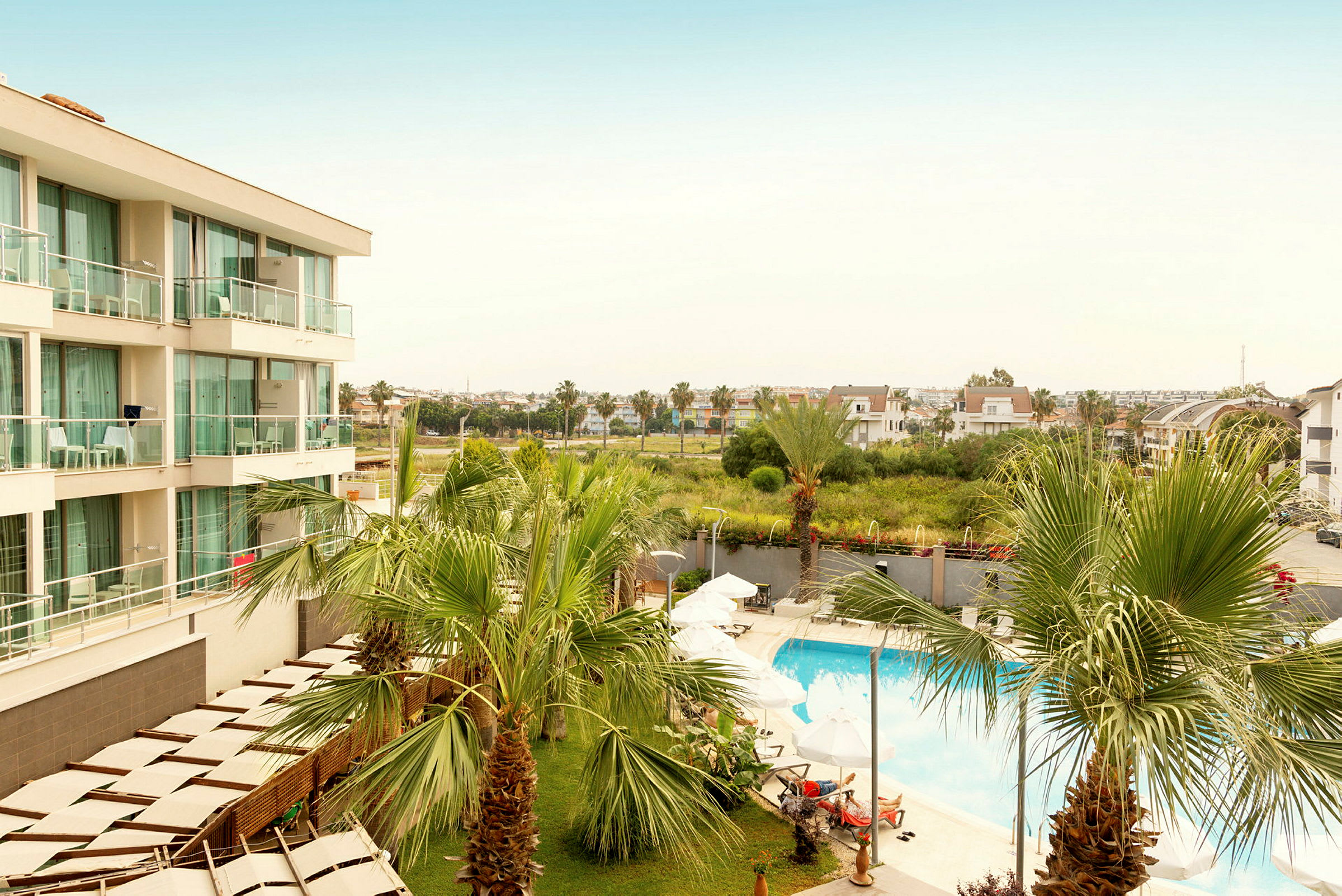 Bild av hotellområde med pool, solstolar och palmer. (AI-genererad text)