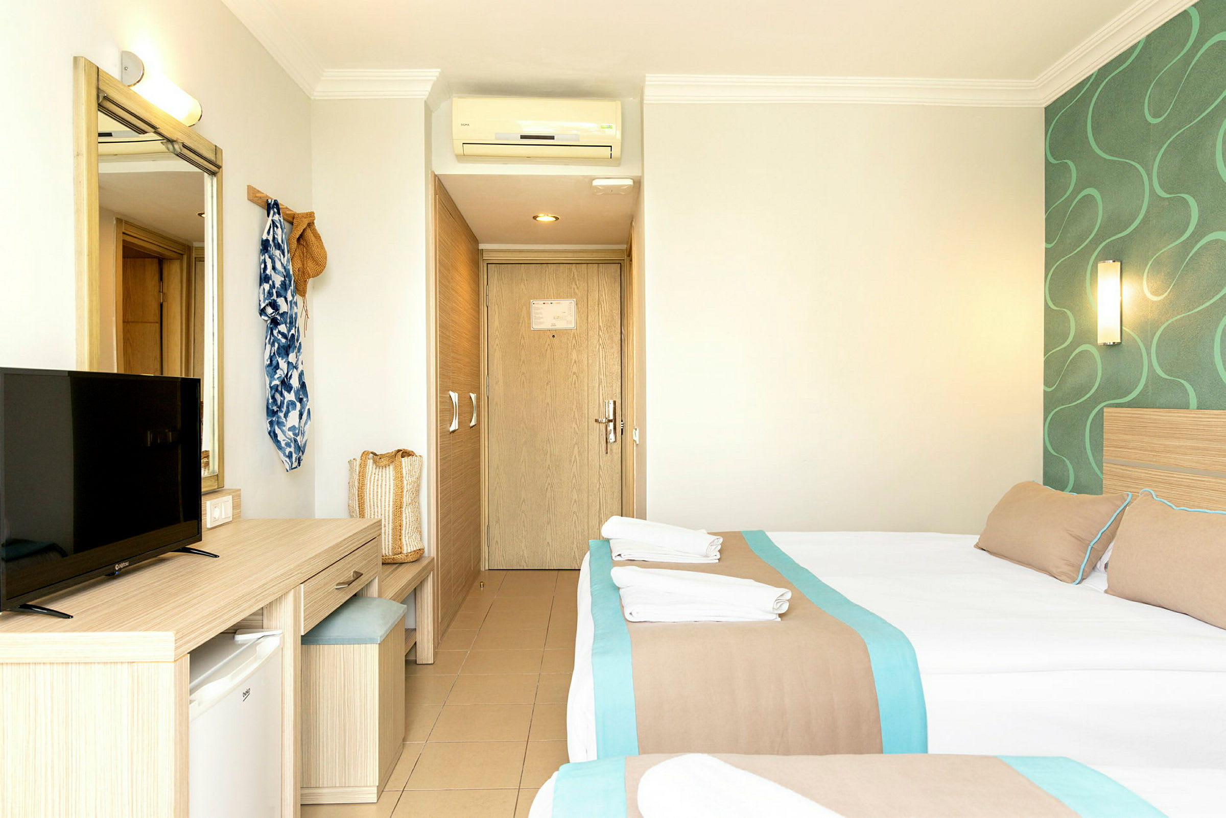Ett hotellrum med två bäddar, en spegel, TV och skrivbord. (AI-genererad text)