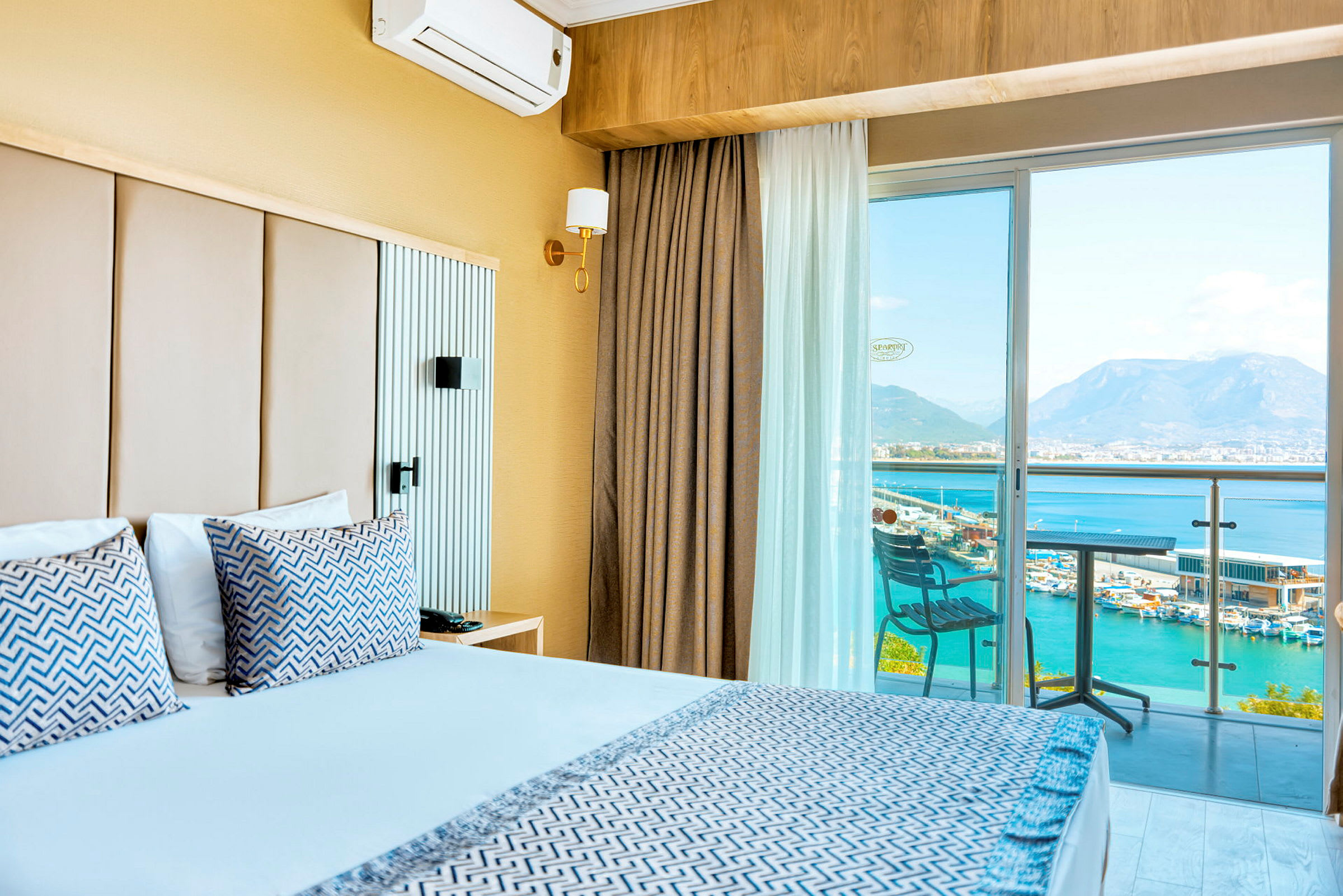 Hotellrum med dubbelsäng, balkong med utsikt över havet och bergen. (AI-genererad text)