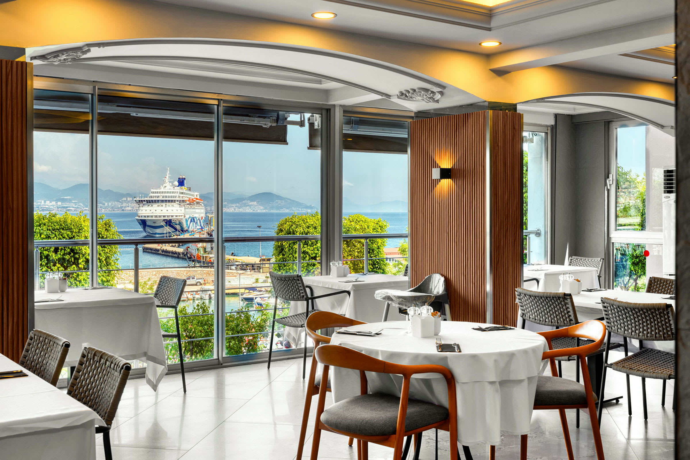 Restaurang med utsikt mot en kryssningsfartyg vid en hamn. (AI-genererad text)