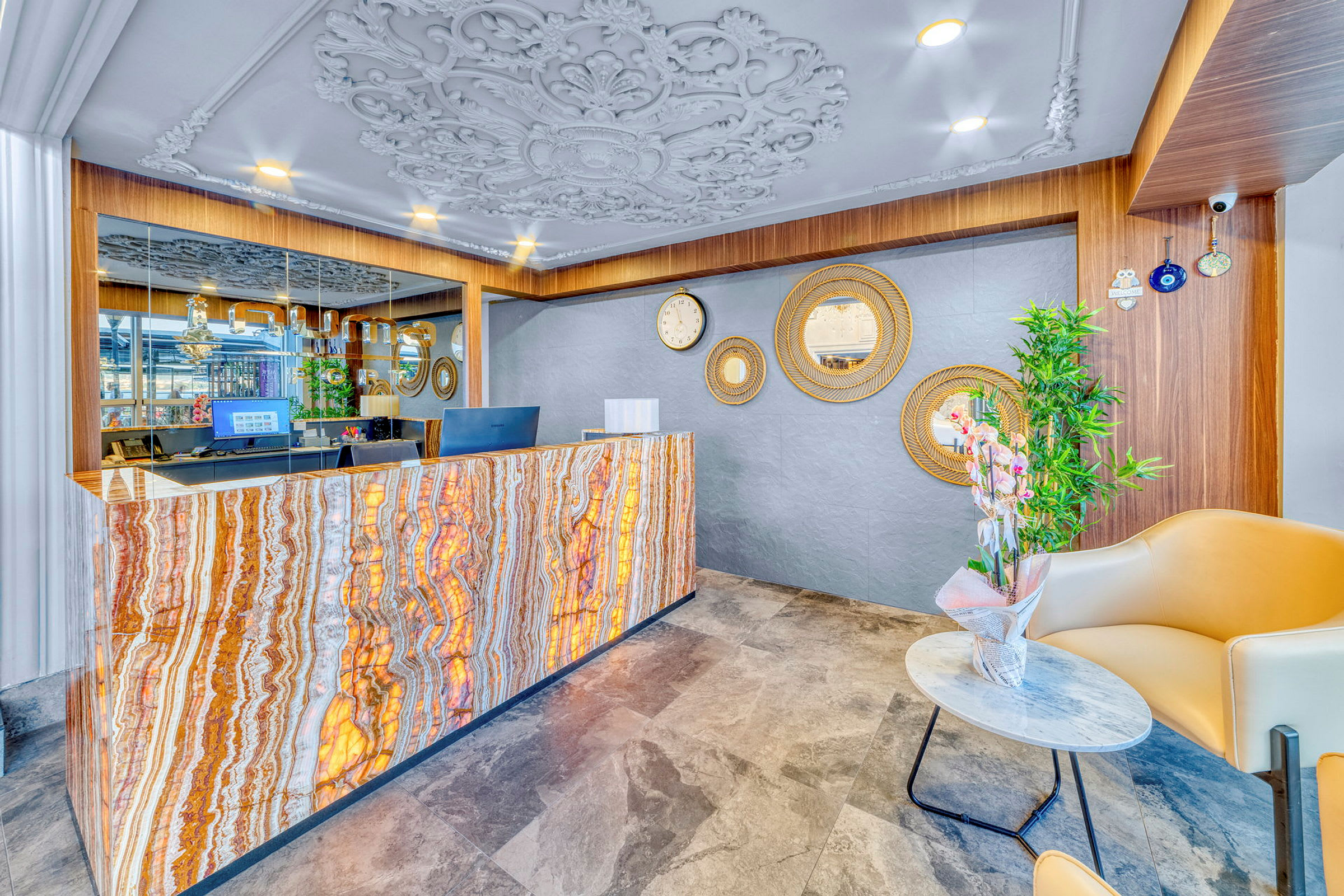 Reception med marmorliknande frontpanel, utsmyckad takdesign och speglar på väggen. (AI-genererad text)