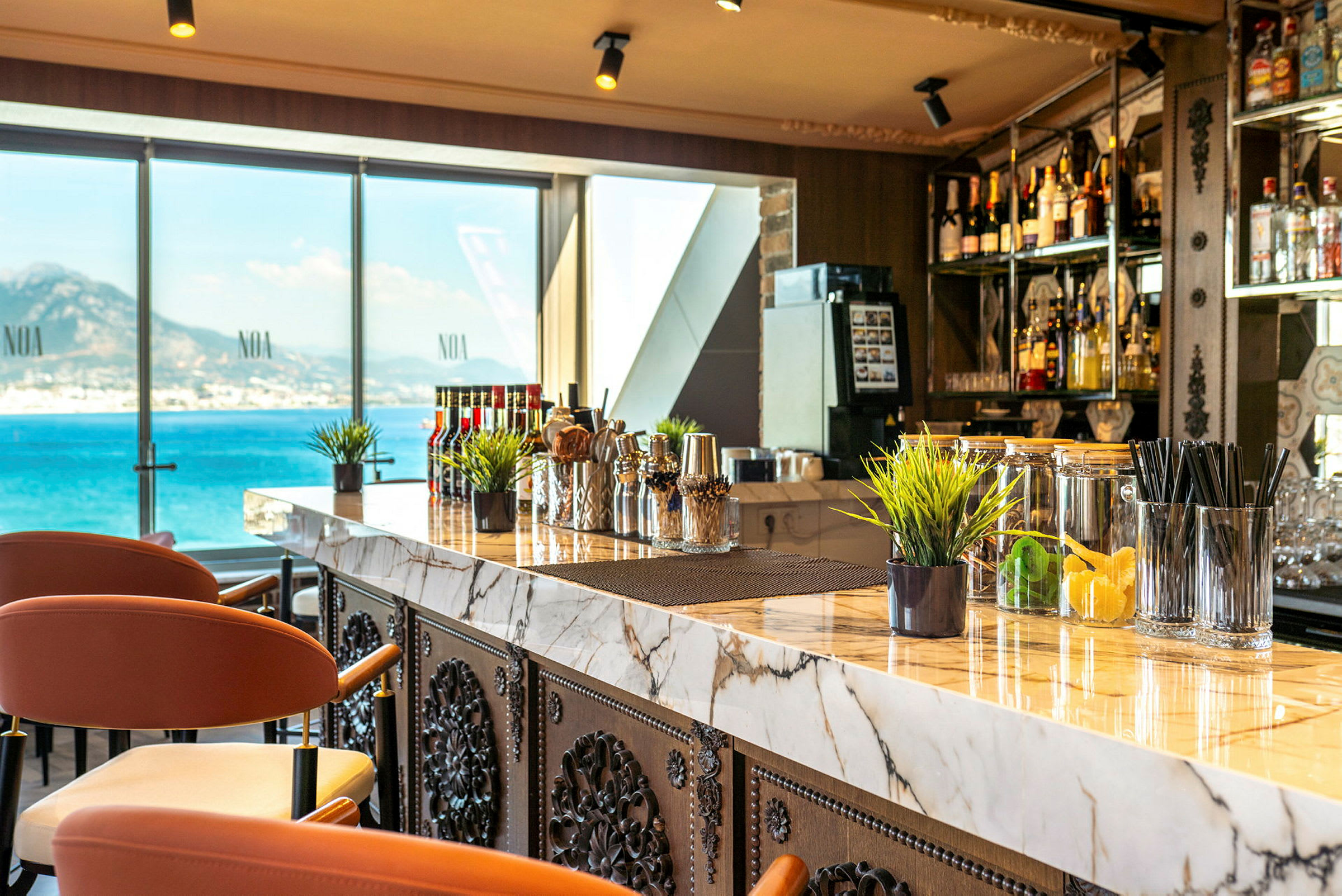En modern bar med marmorbänk och stolar samt utsikt över havet genom stora fönster. (AI-genererad text)