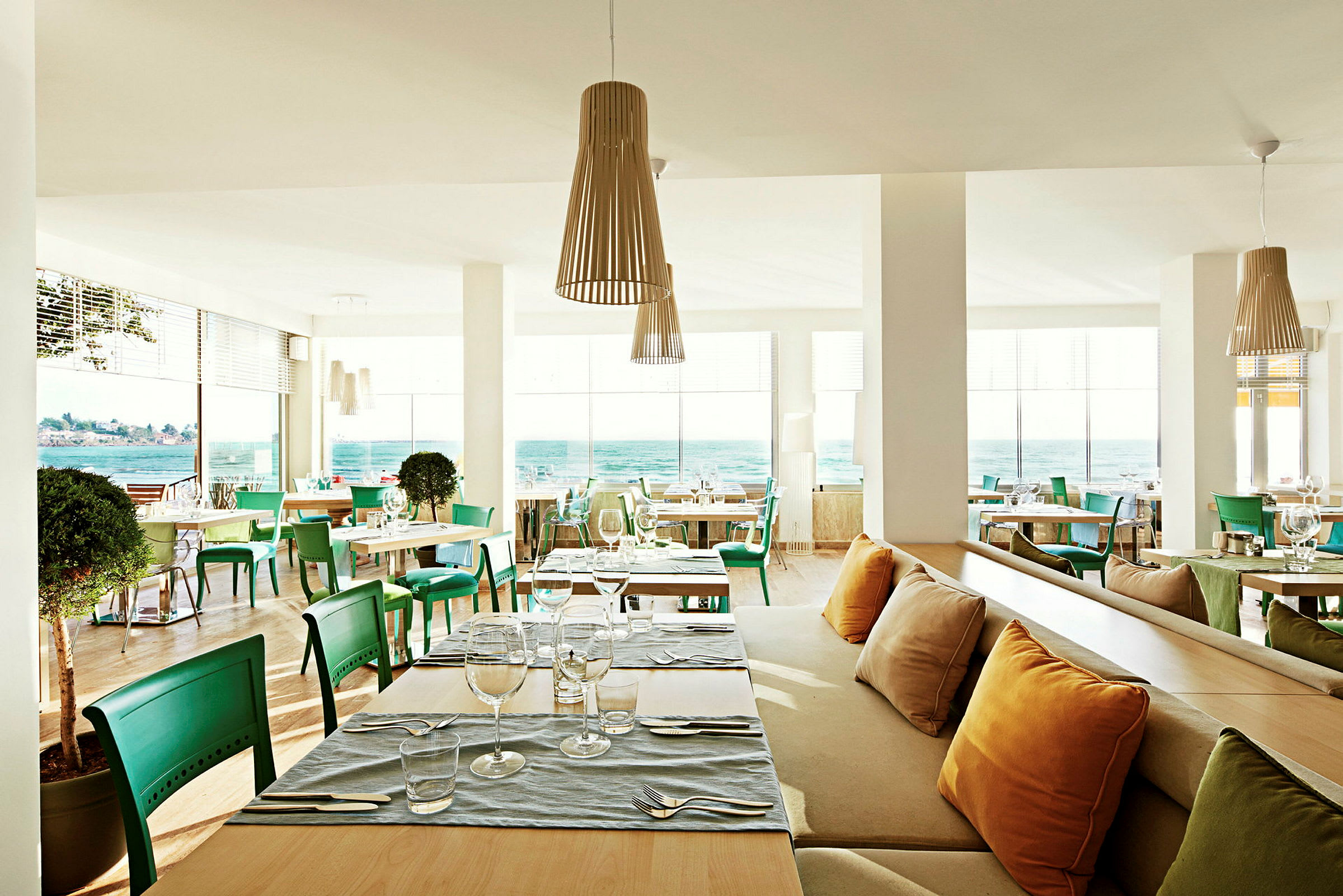 Modern restaurang med havsutsikt och gröna stolar. (AI-genererad text)