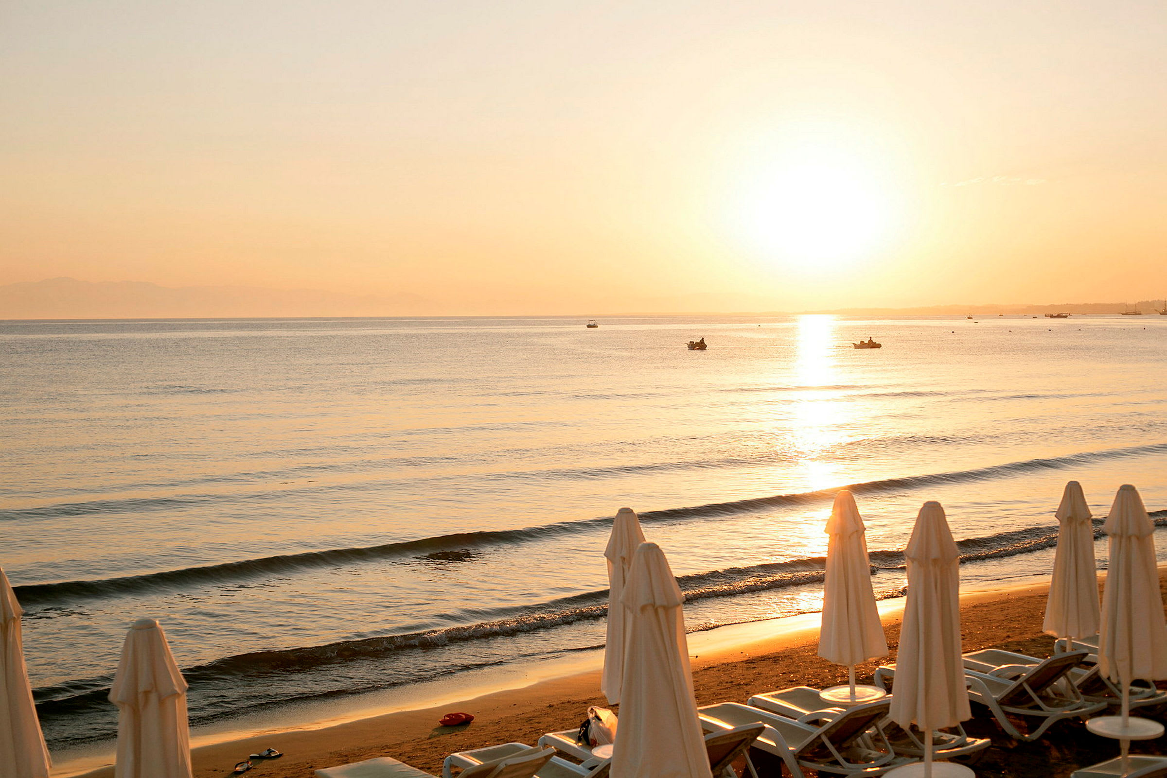 Strand i solnedgång med solstolar och parasoller. (AI-genererad text)