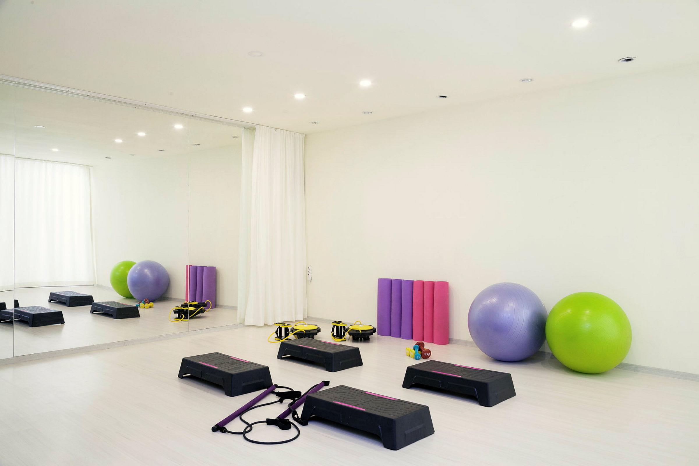 Ett träningsrum med stepbrädor, gymbollar och yogamattor. (AI-genererad text)