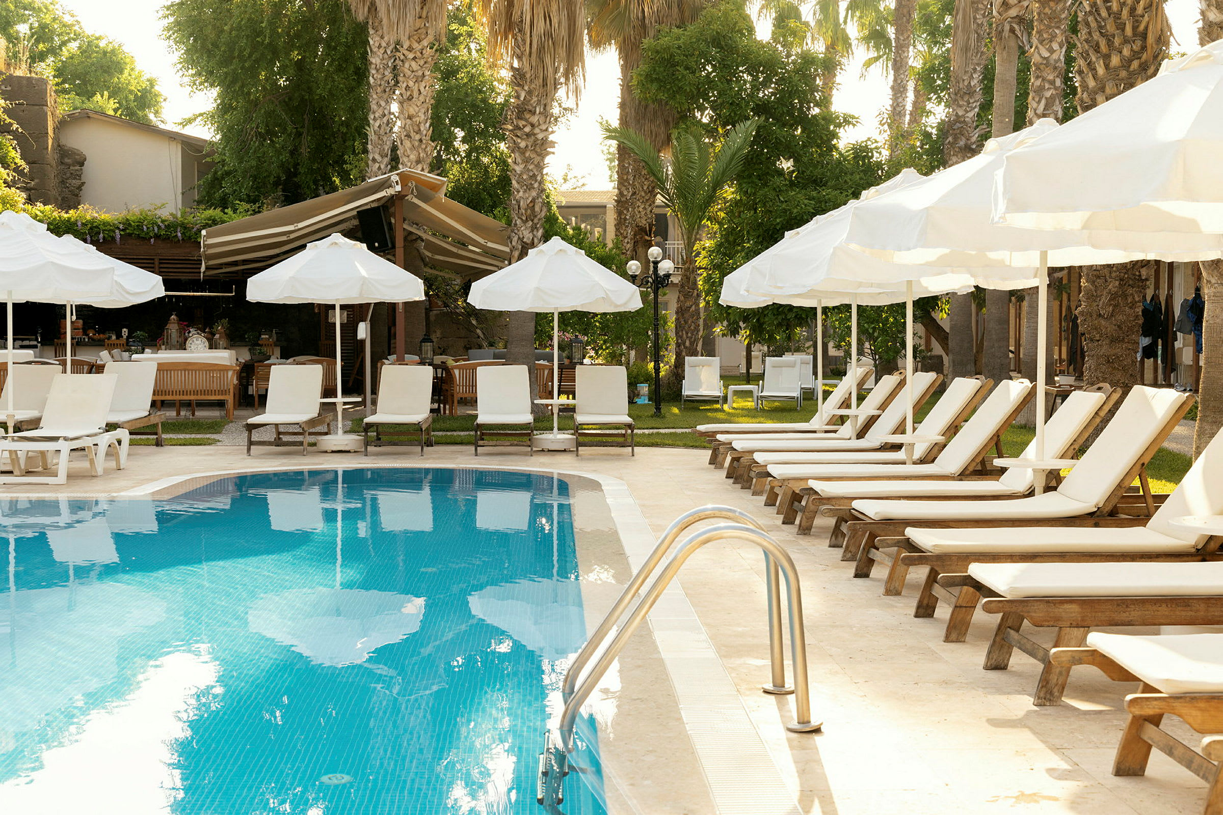 Hotellpool med solstolar och parasoller vid kanten. (AI-genererad text)