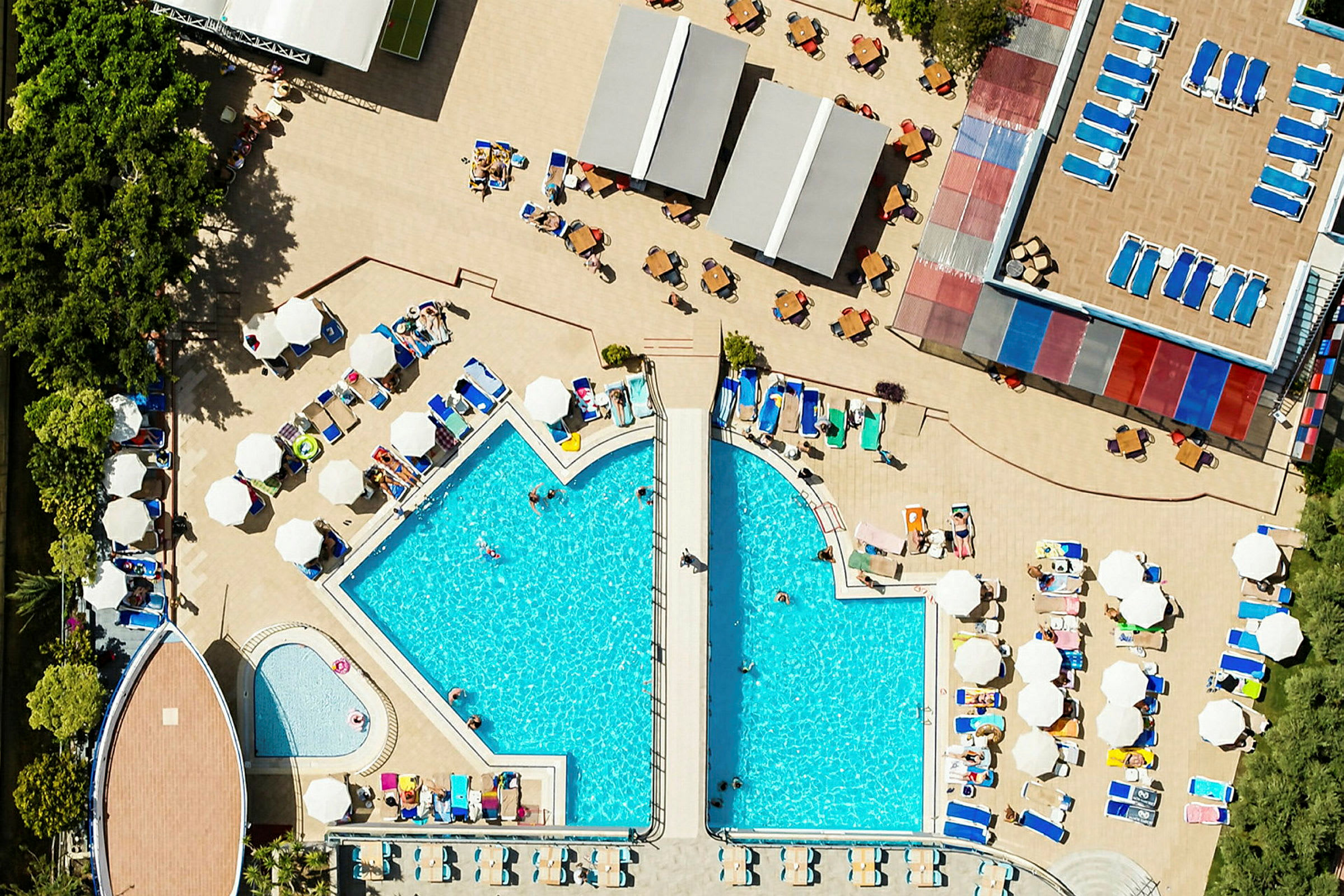 En översiktsbild av en hotellpool med omgivande solstolar och parasoller. (AI-genererad text)