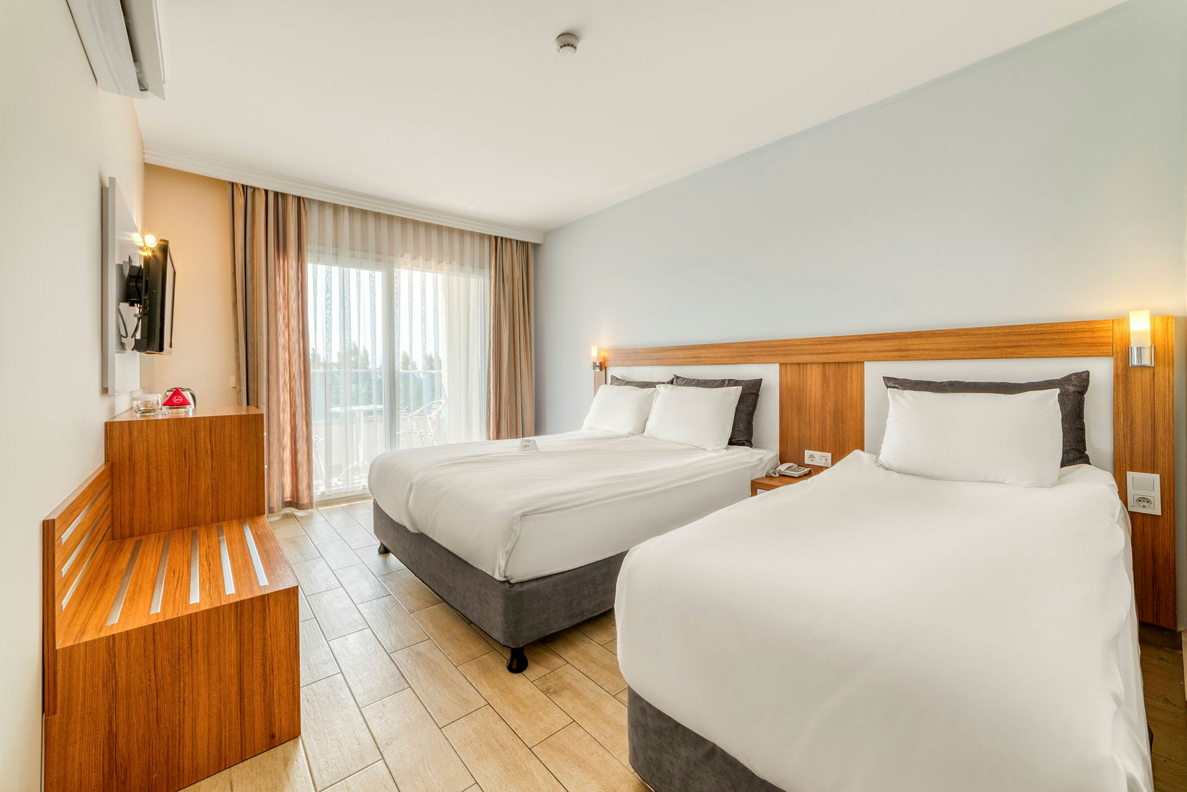 Modernt hotellrum med två sängar, ljusa färger och stora fönster. (AI-genererad text)