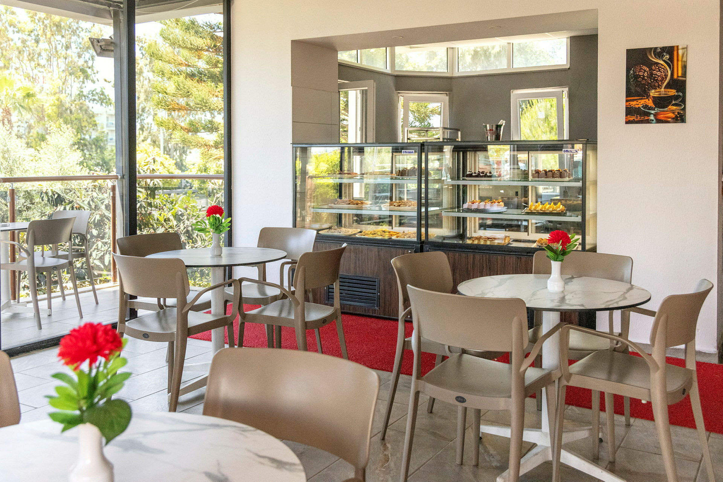 Bild på ett café med bord och stolar samt en glasmonter med bakverk. (AI-genererad text)